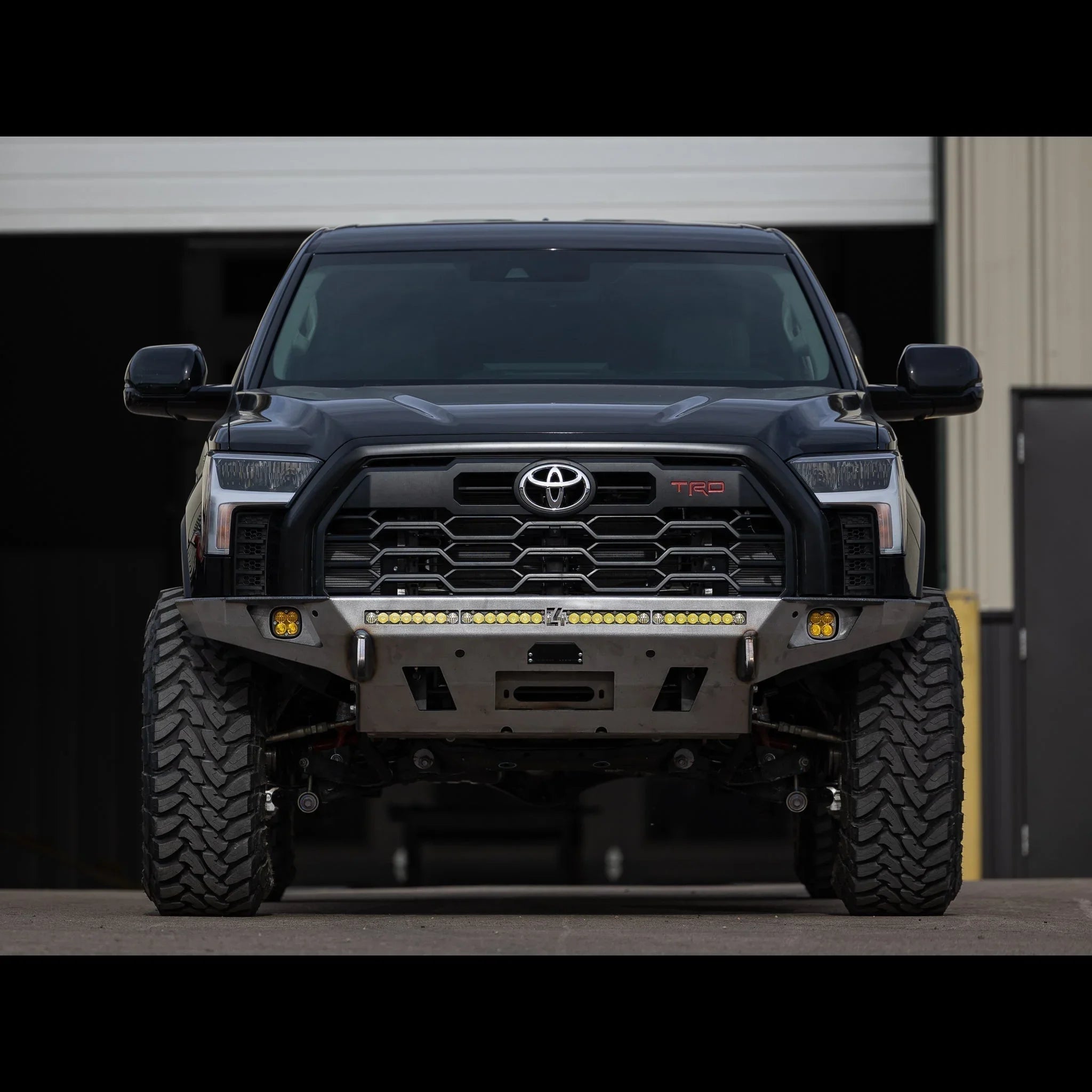 Toyota Tundra with overland front bumper, off-road tires, and LED light bar, frontal view