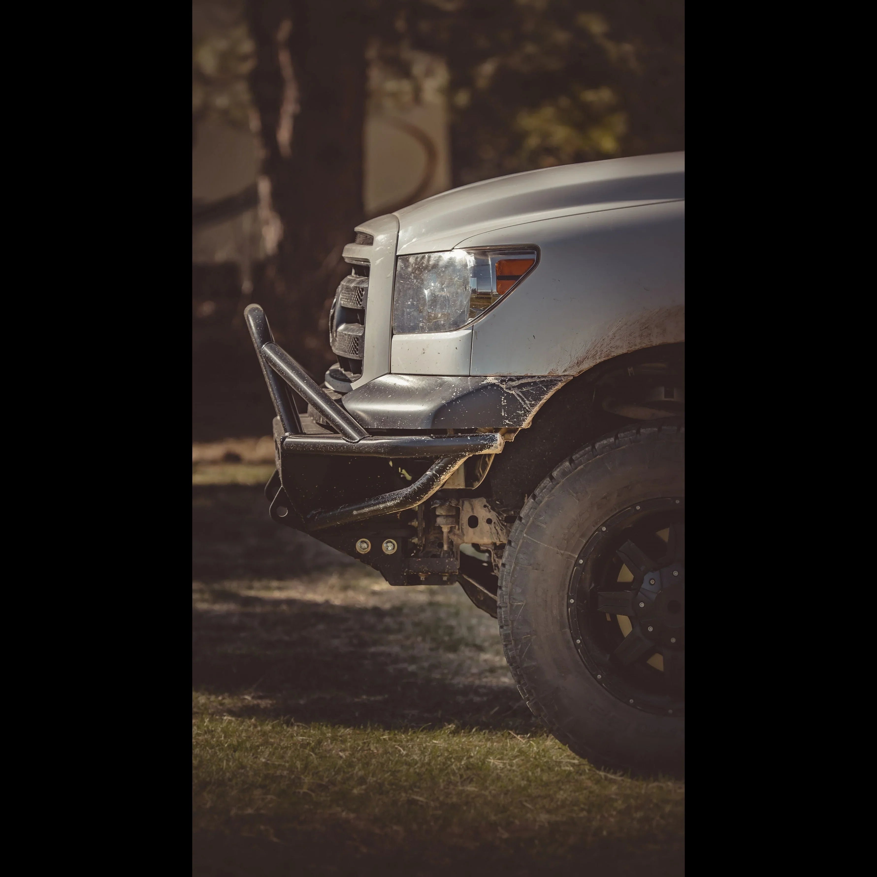 Off-road steel front bumper and large tire on Toyota truck outdoors