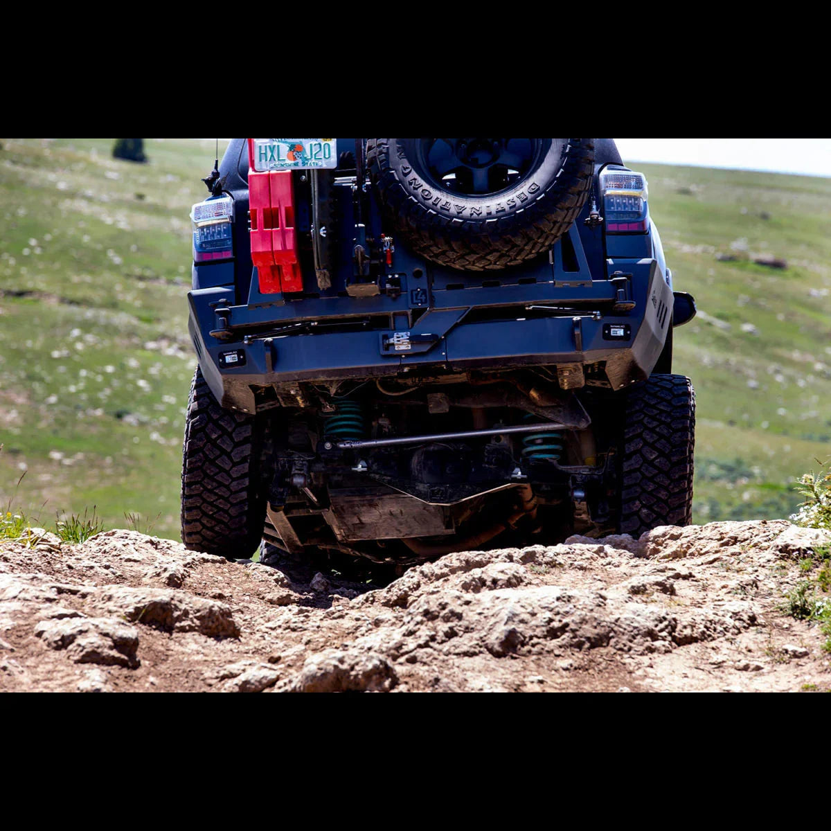 Off-road vehicle with skid plate climbing rocky trail, showing adventure gear and rugged tires