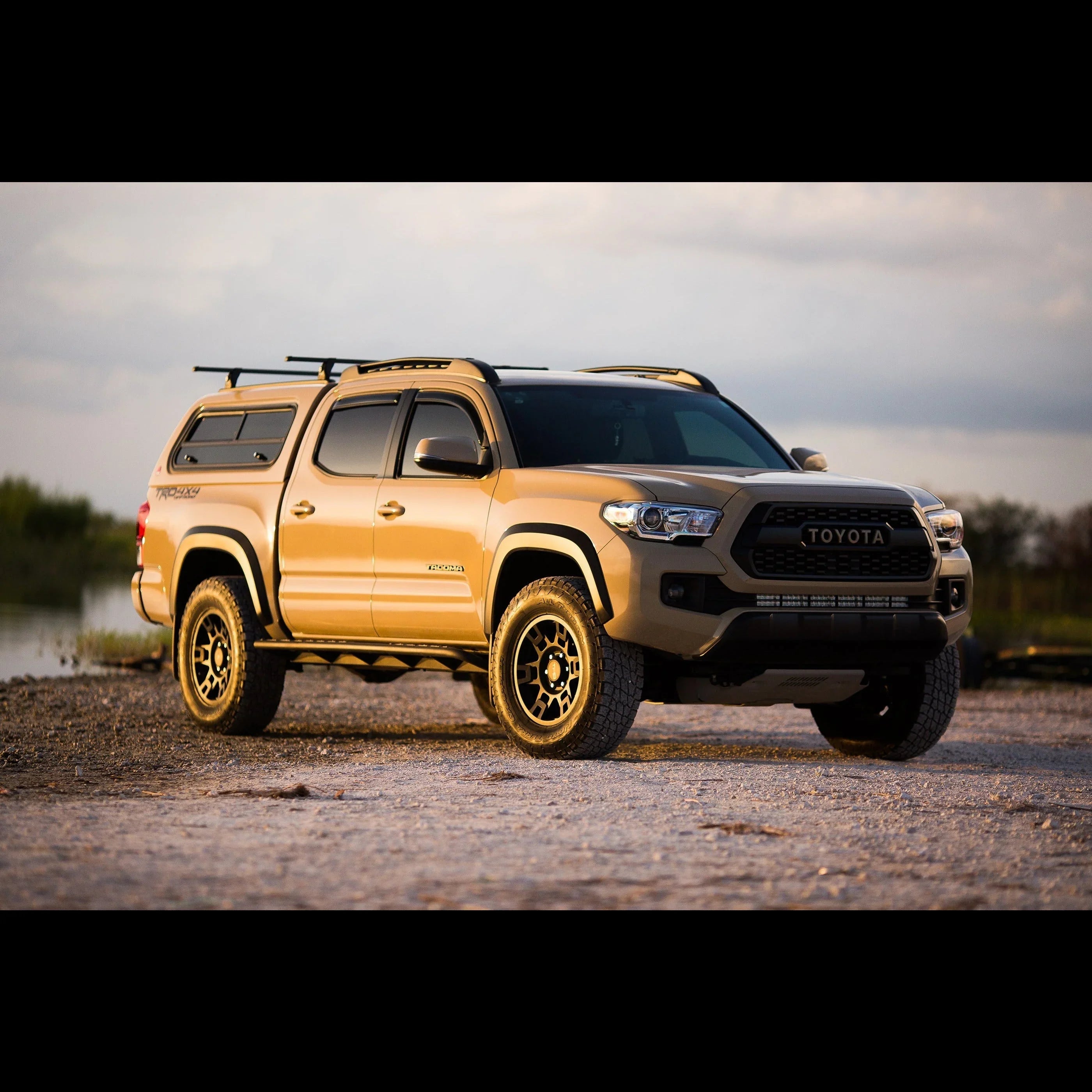 2016 Toyota Tacoma with rock sliders, off-road wheels, and roof rack parked outdoors
