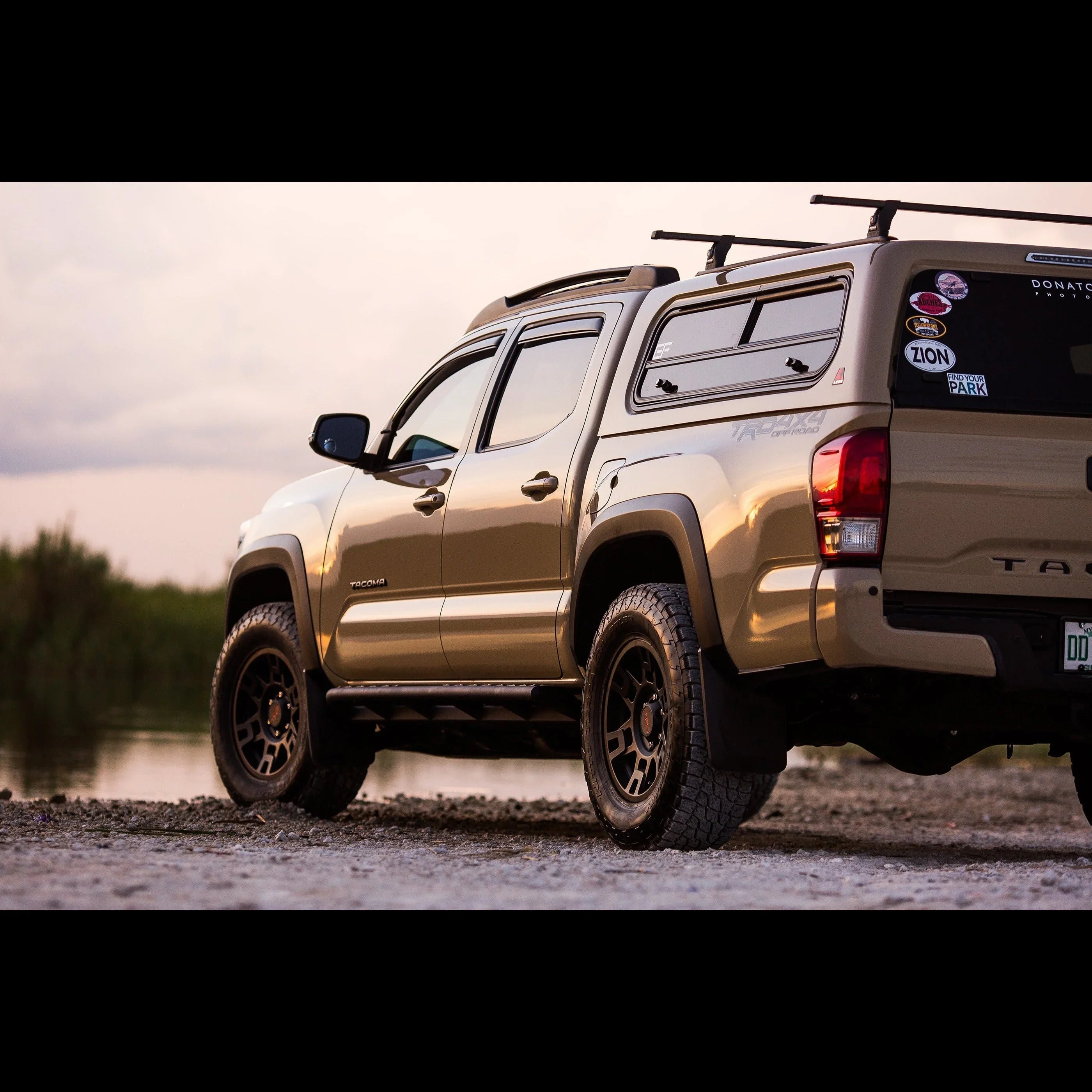 Toyota Tacoma with off-road rock sliders on gravel, outdoors at sunset