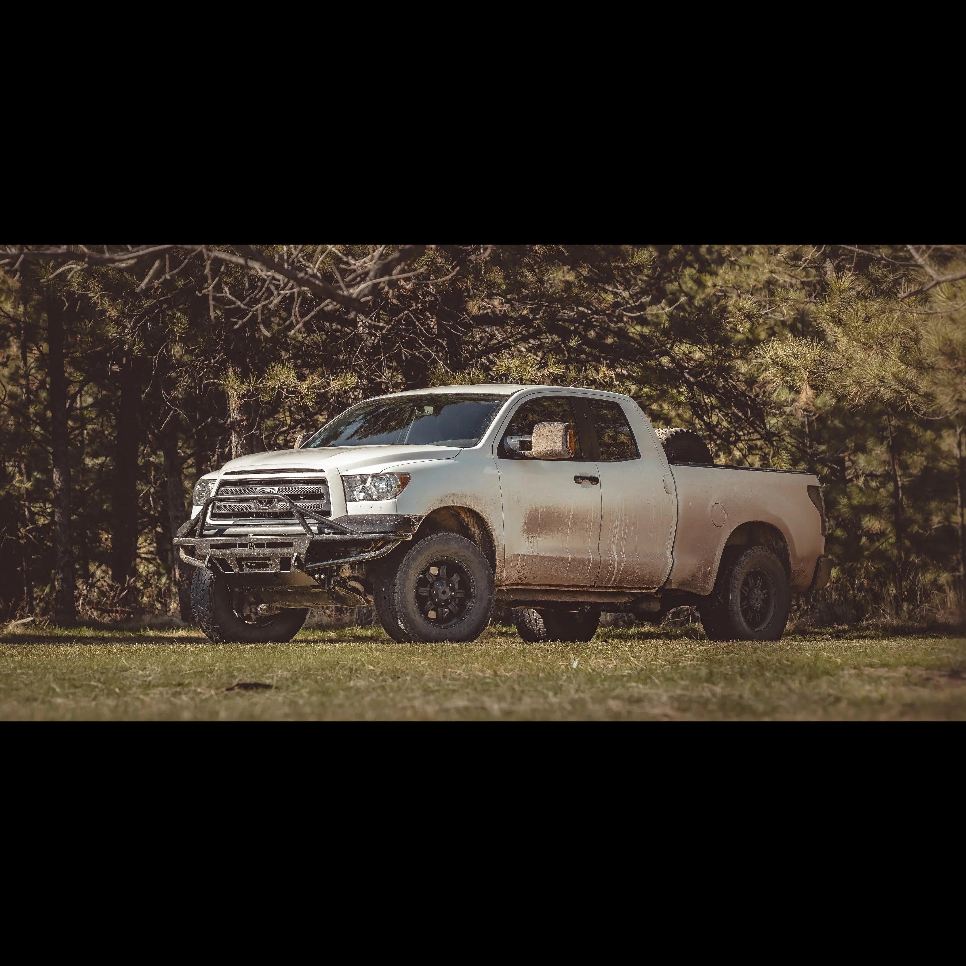 Toyota Tundra pickup truck with off-road front bumper parked in a forest clearing