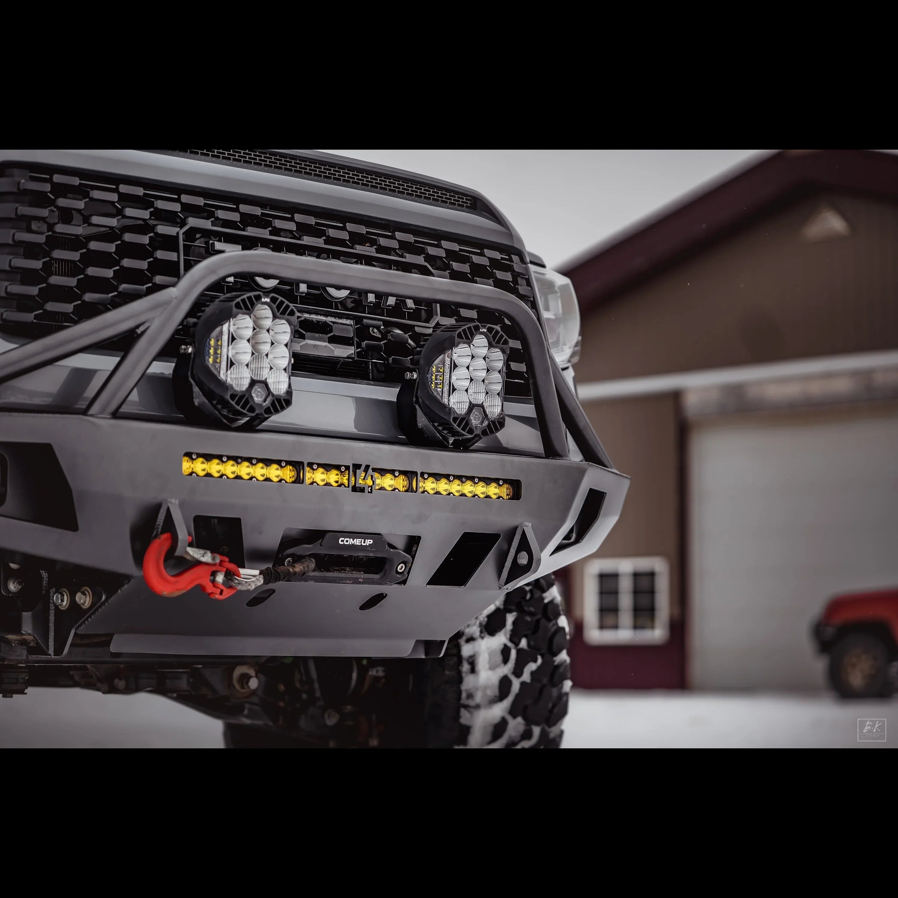 Off-road vehicle front bumper with winch, LED light bar, and recovery points in snowy setting