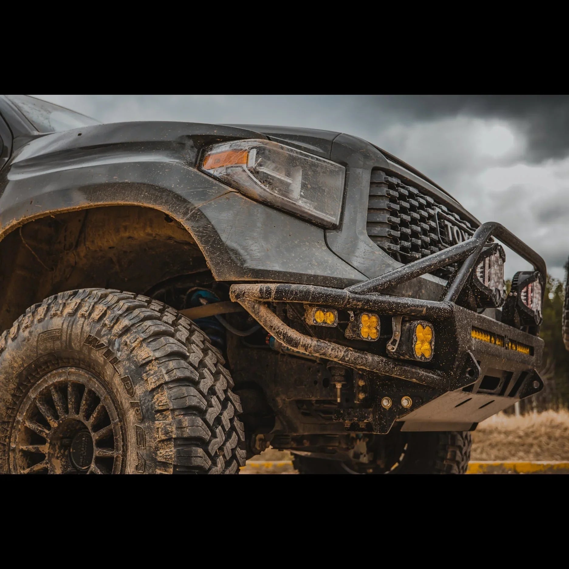 Off-road Toyota truck with mud-terrain tires and rugged front bumper with LED lights