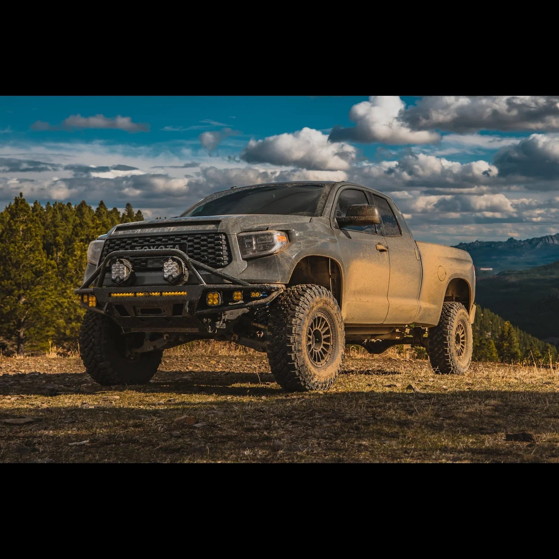 Lifted Toyota Tundra off-road truck with rugged front bumper and LED lights in a mountain landscape