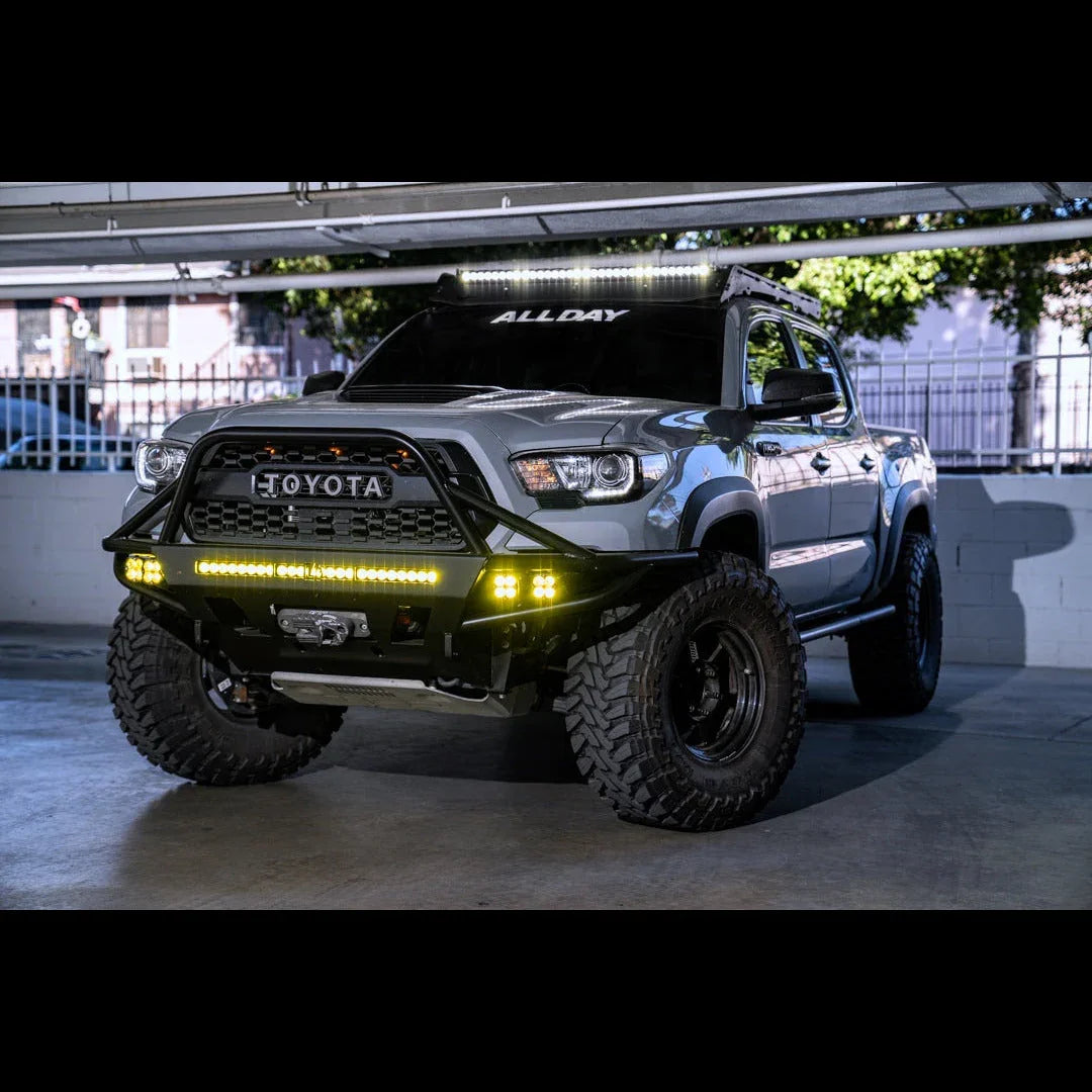 Toyota Tacoma off-road truck with custom bumper, LED light bars, and rugged tires in garage
