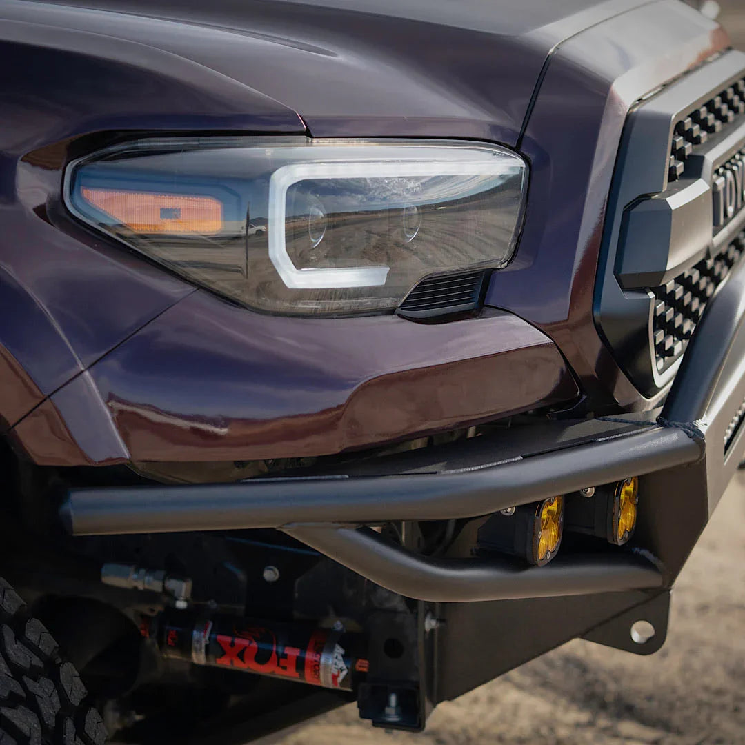 Close-up of Toyota Tacoma front bumper with off-road fog lights and Fox shock absorber