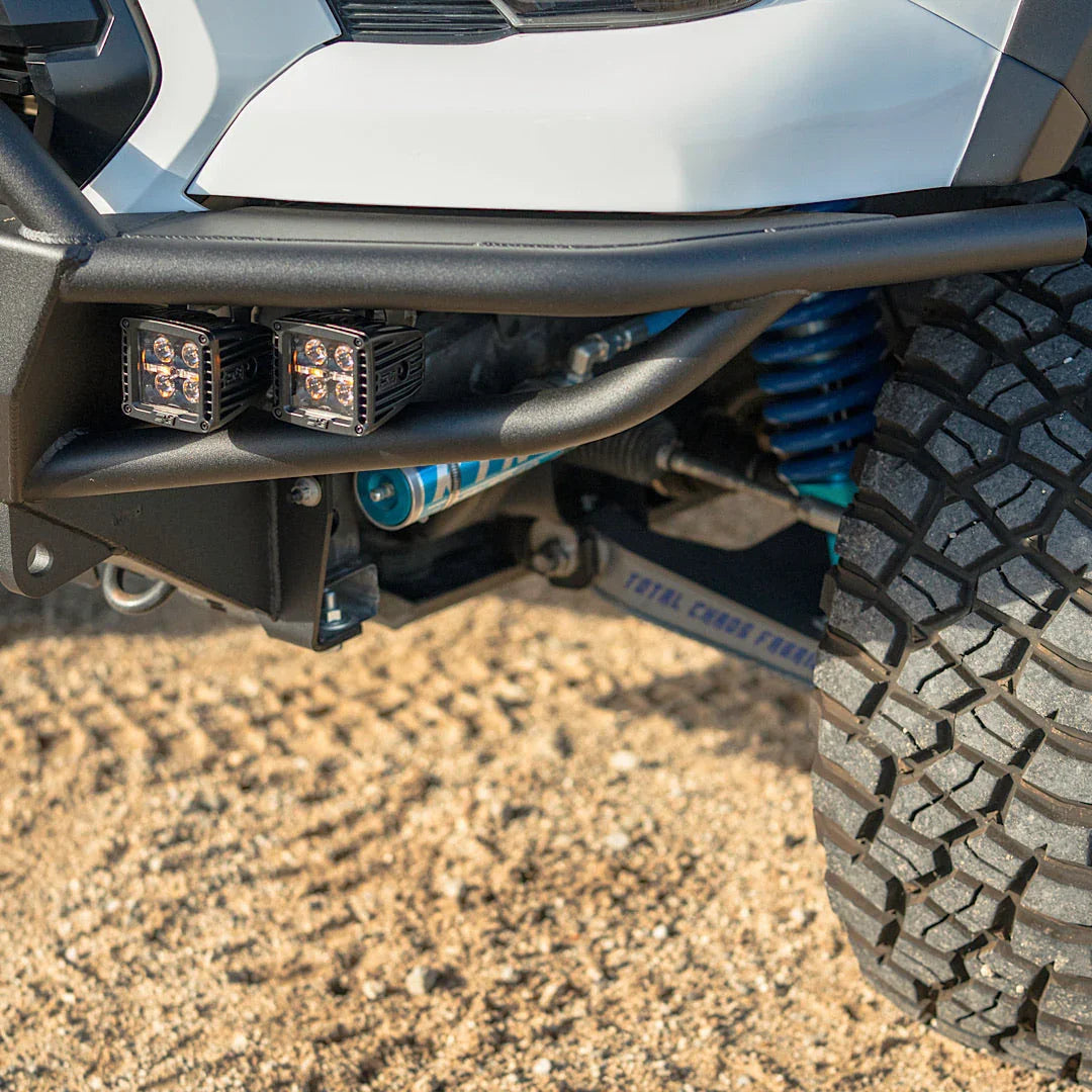 Off-road truck front bumper with LED pod lights, suspension, and all-terrain tire on dirt