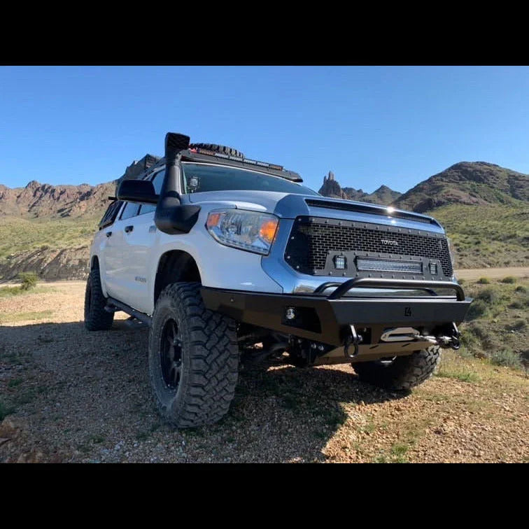 White Toyota Tundra with off-road bumper, roof rack, and snorkel parked in desert terrain