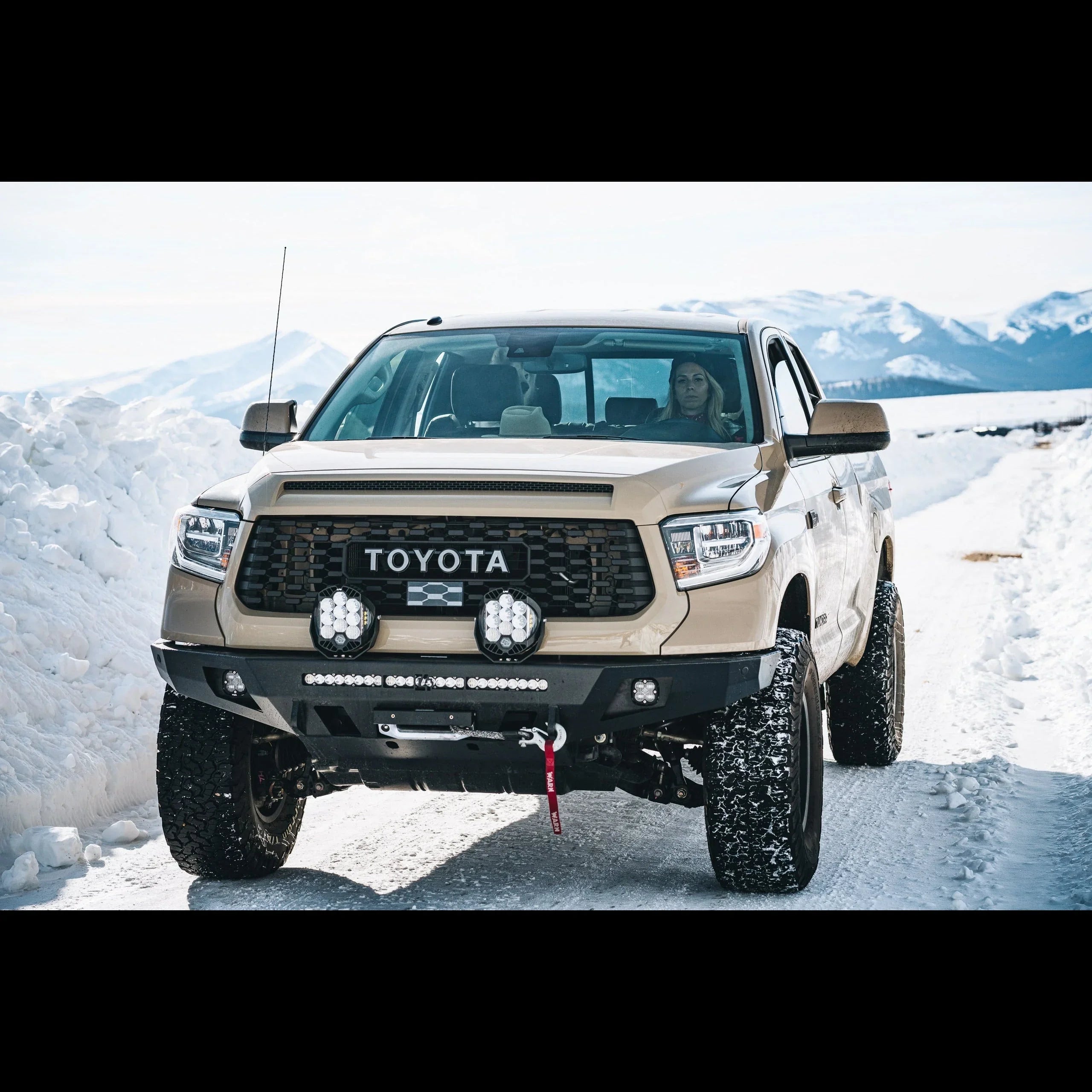 Toyota Tundra with off-road accessories driving on snowy mountain trail