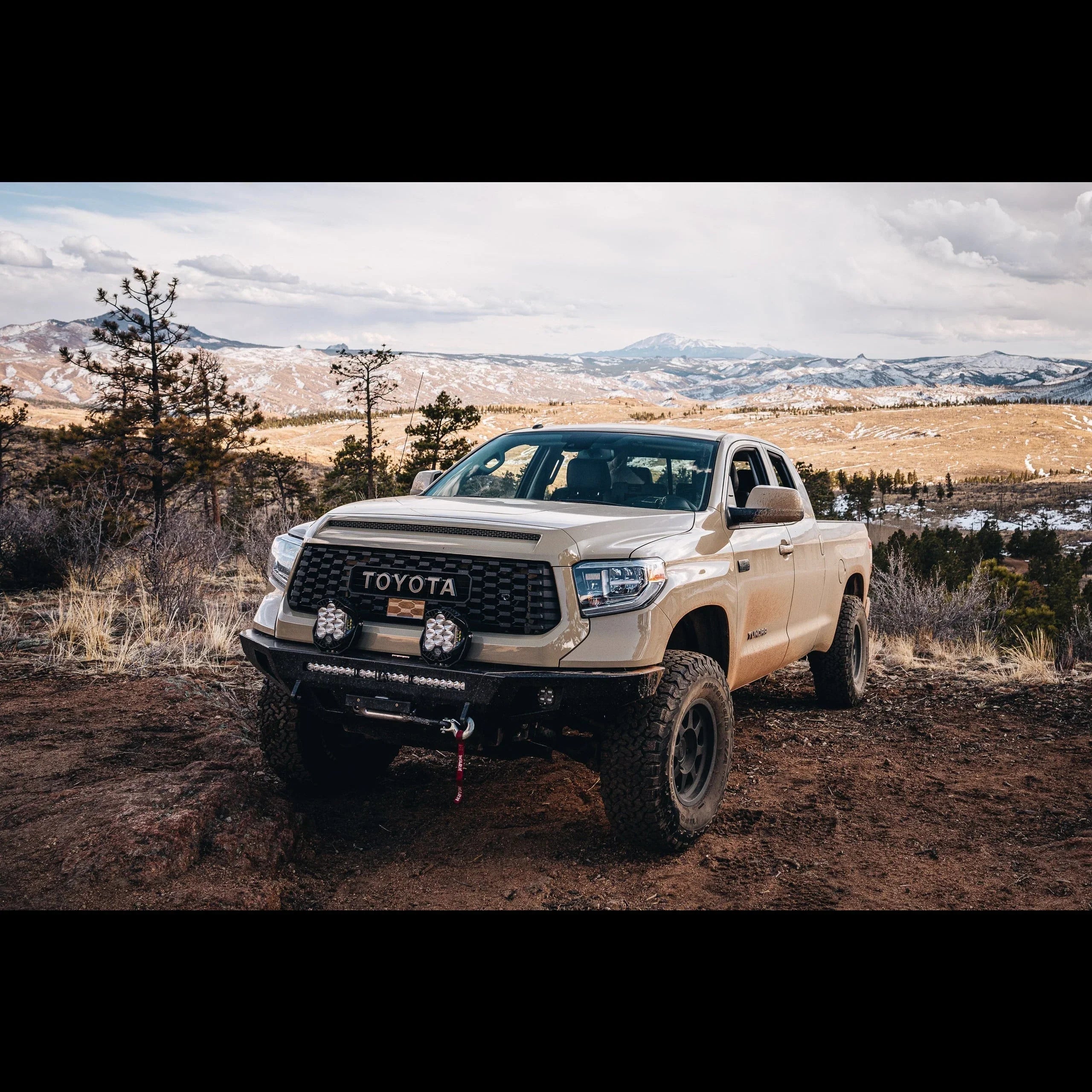 Toyota Tundra off-road truck with aftermarket bumper and lights parked on a mountain trail