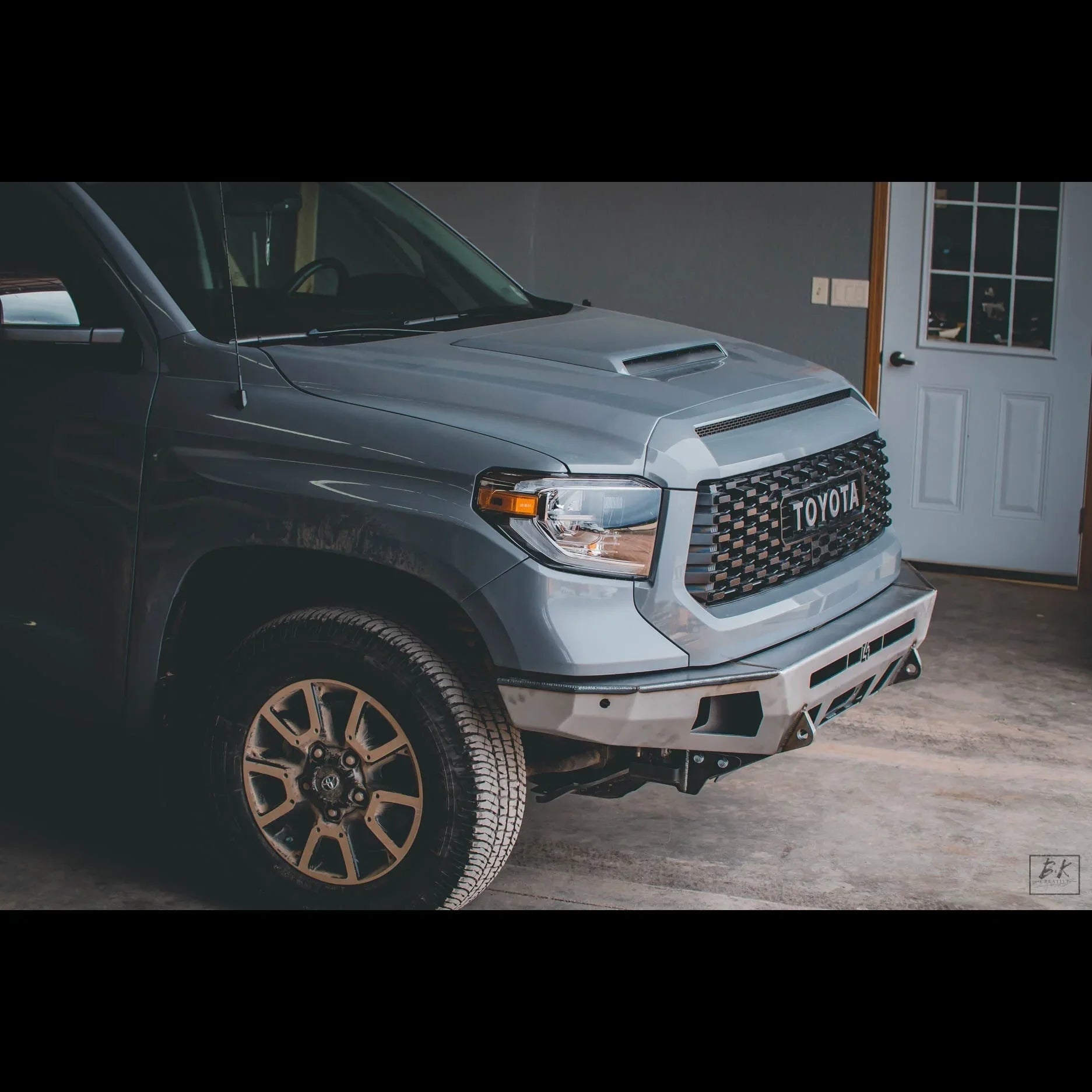 Toyota Tundra front end with aftermarket grille and off-road bumper parked indoors