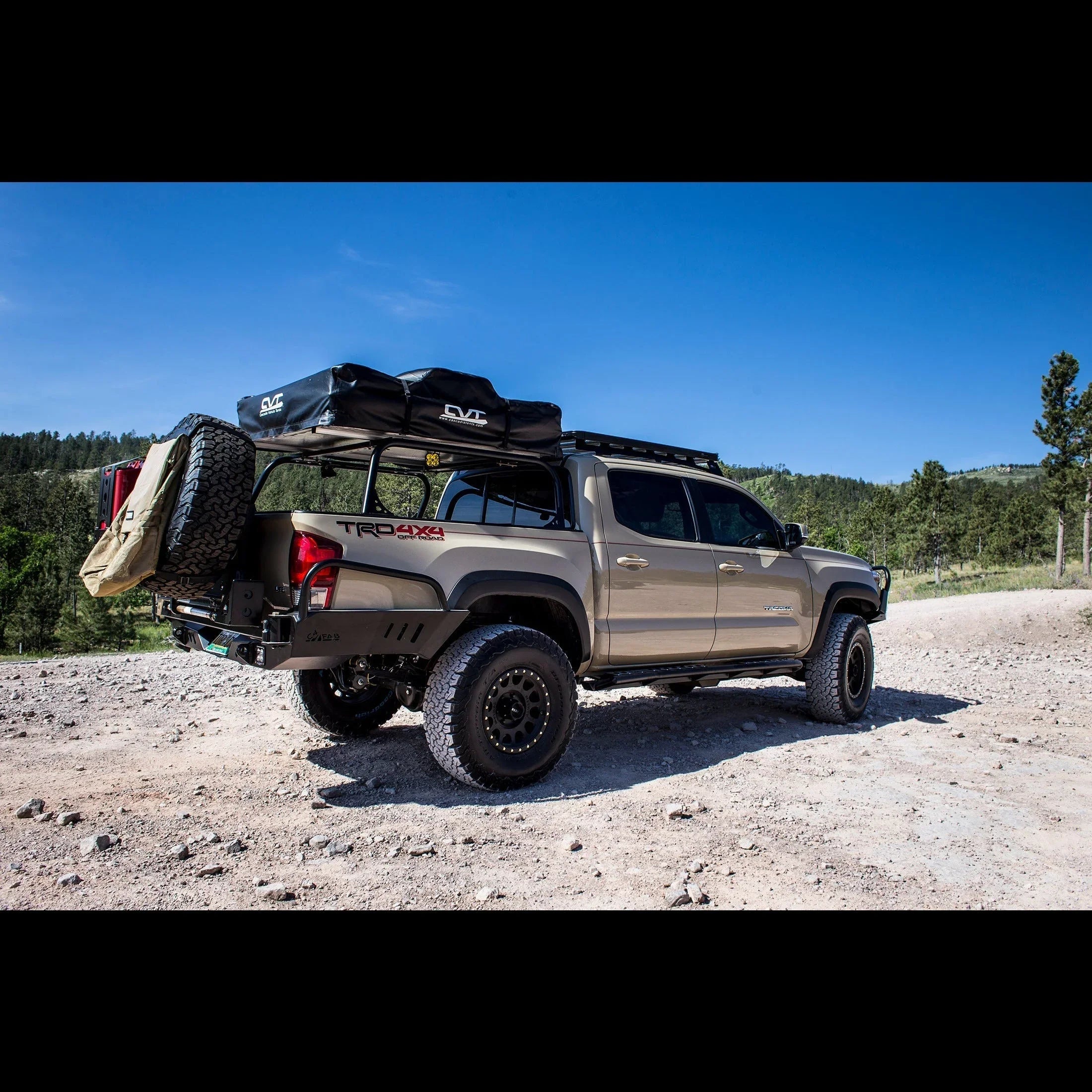Toyota Tacoma TRD 4x4 overland truck with roof racks and camping gear parked on mountain trail