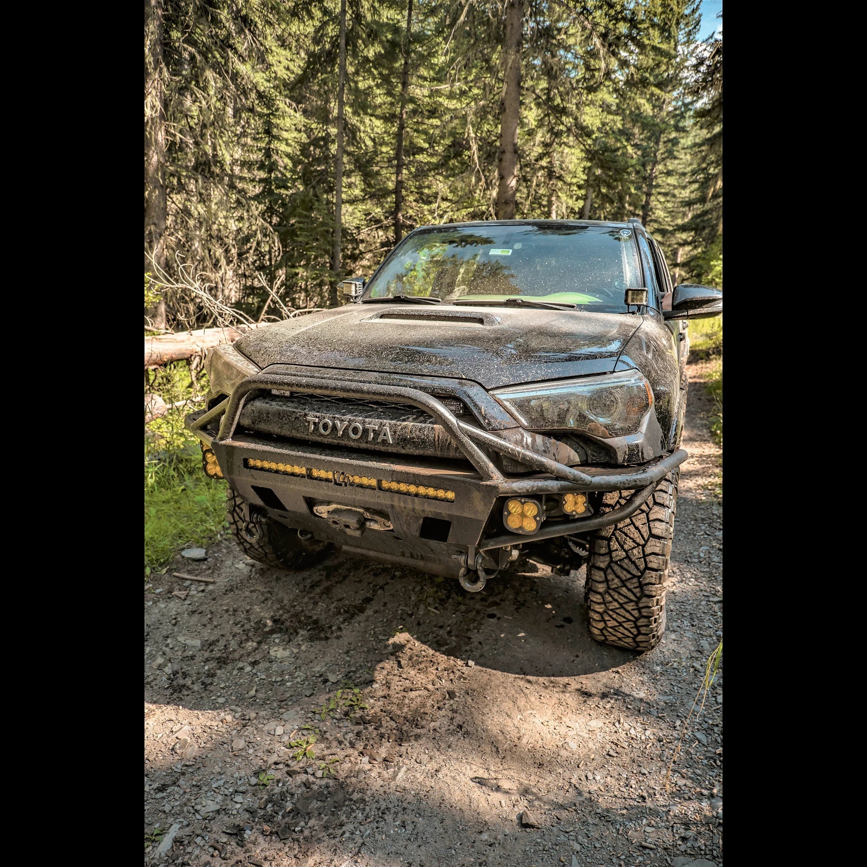 Toyota Tacoma with off-road bumper and lights on forest trail, overland adventure vehicle