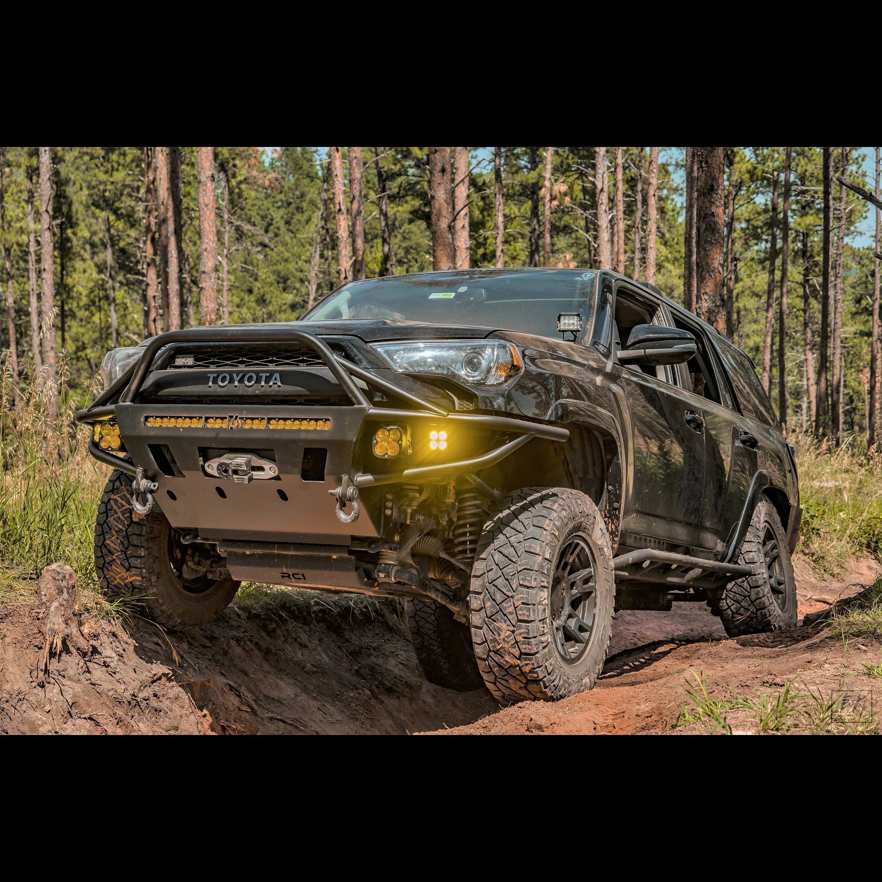 Toyota 4Runner with off-road bumper, winch, and LED lights on forest trail