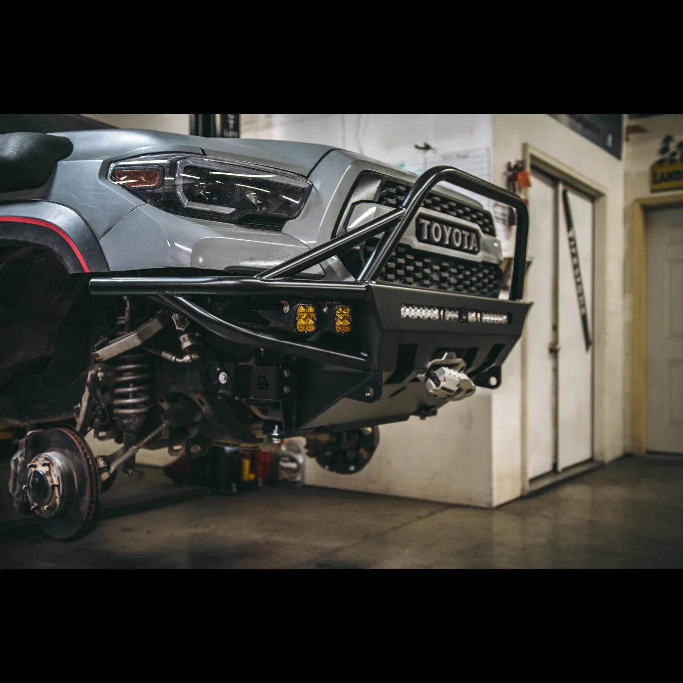 Toyota Tacoma front bumper with winch mount, off-road lights, and grille guard in garage