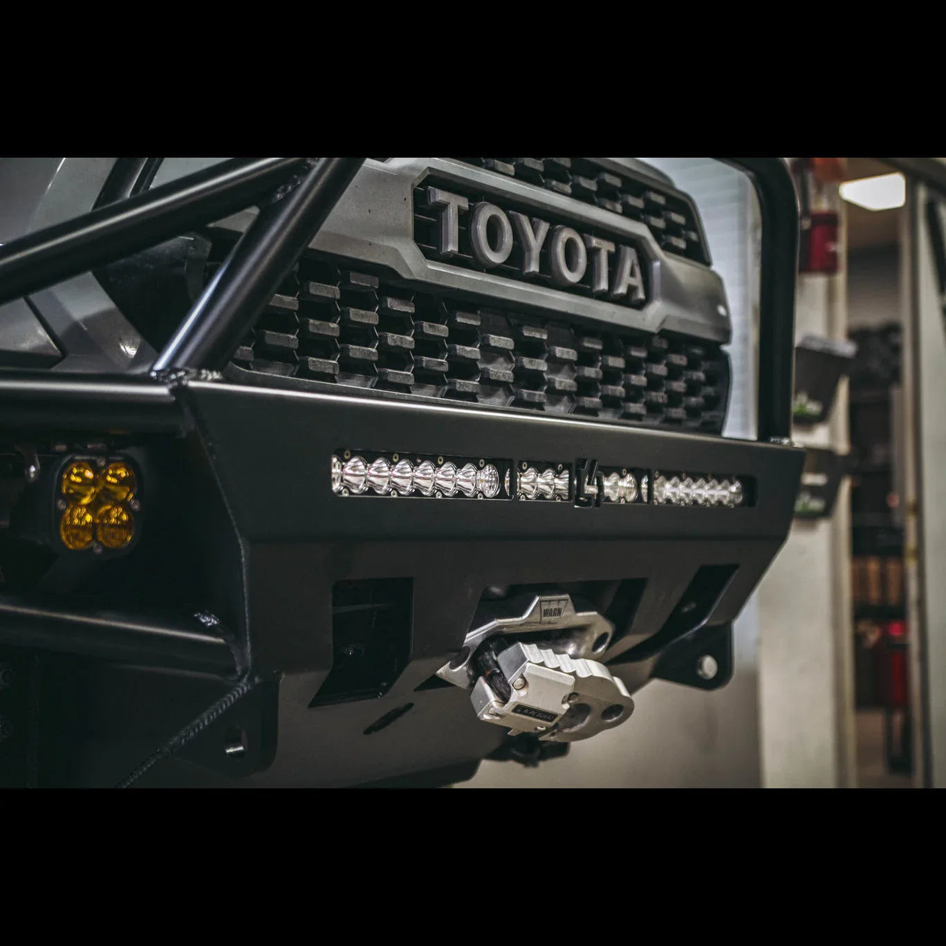 Toyota Tacoma front grille with off-road steel bumper, LED lights, and recovery winch.