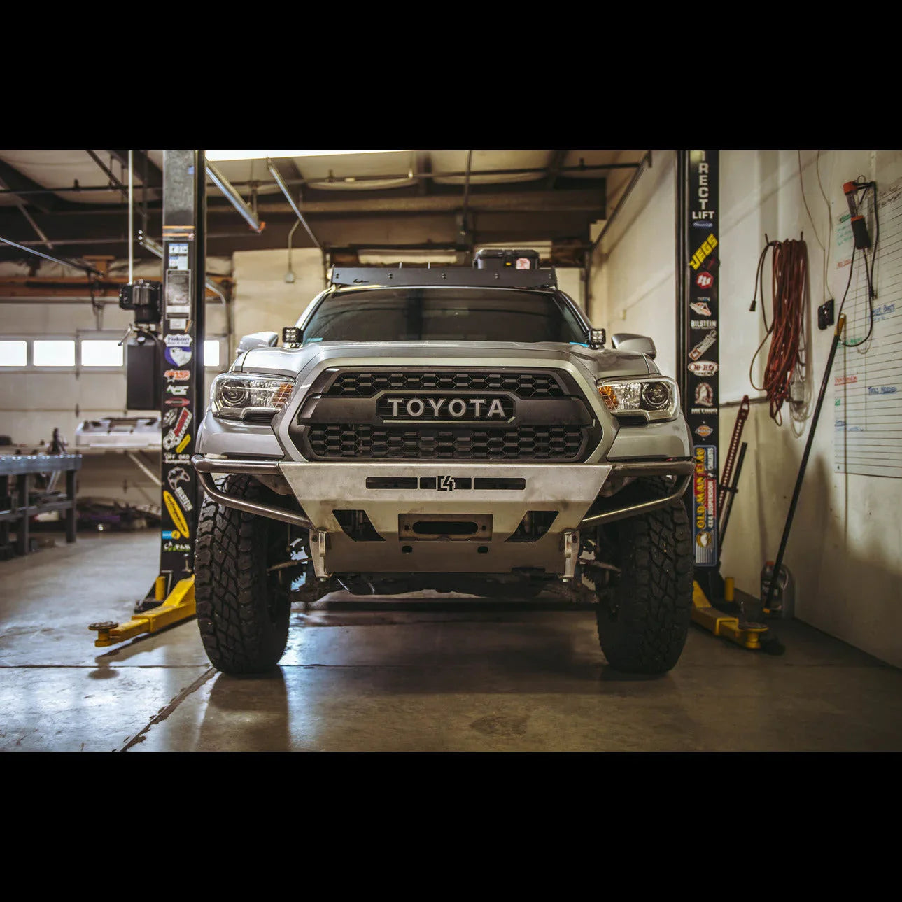 Front view of modified Toyota Tacoma with off-road bumper in a garage setting