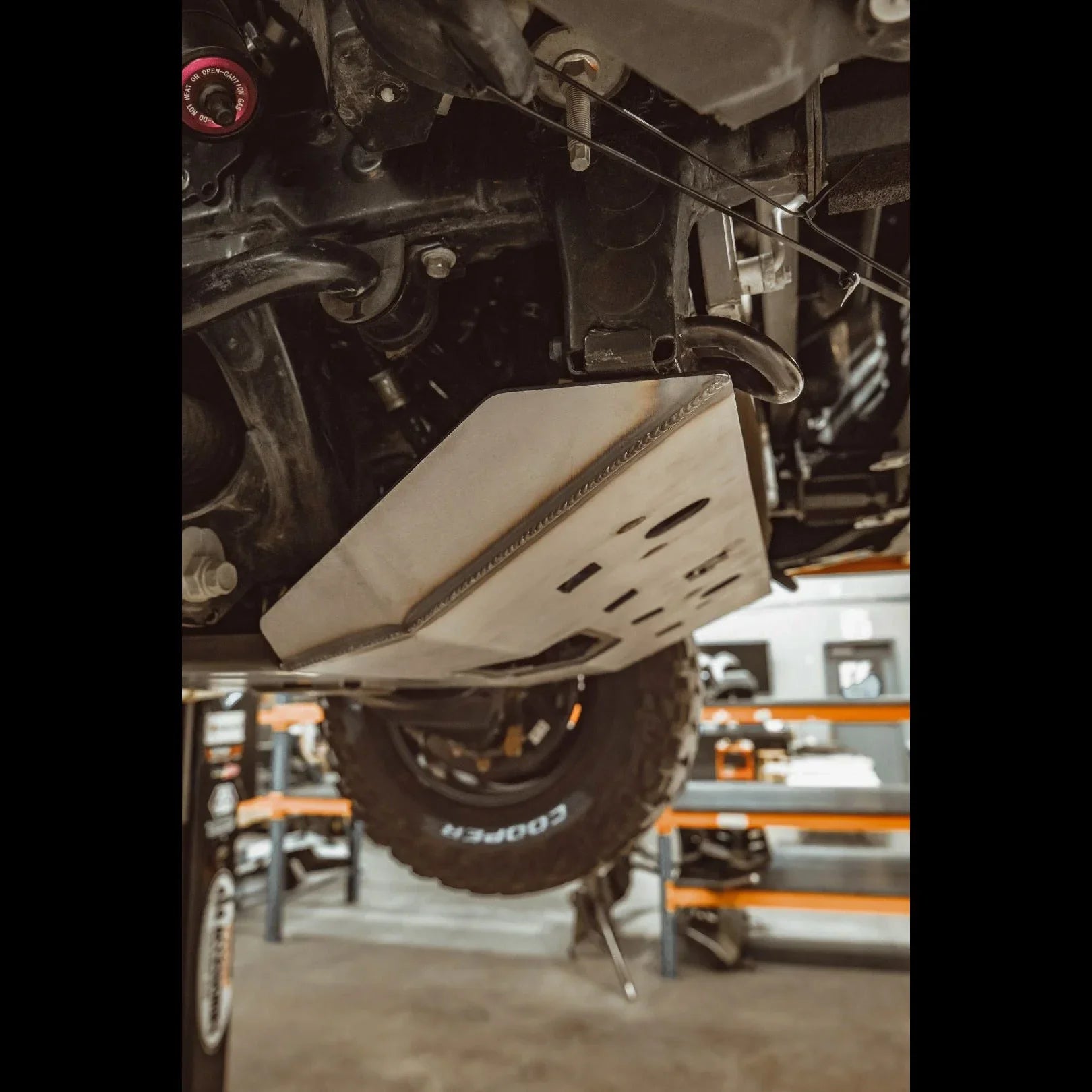 Steel skid plate installed under off-road vehicle, lift in garage, protective undercarriage armor