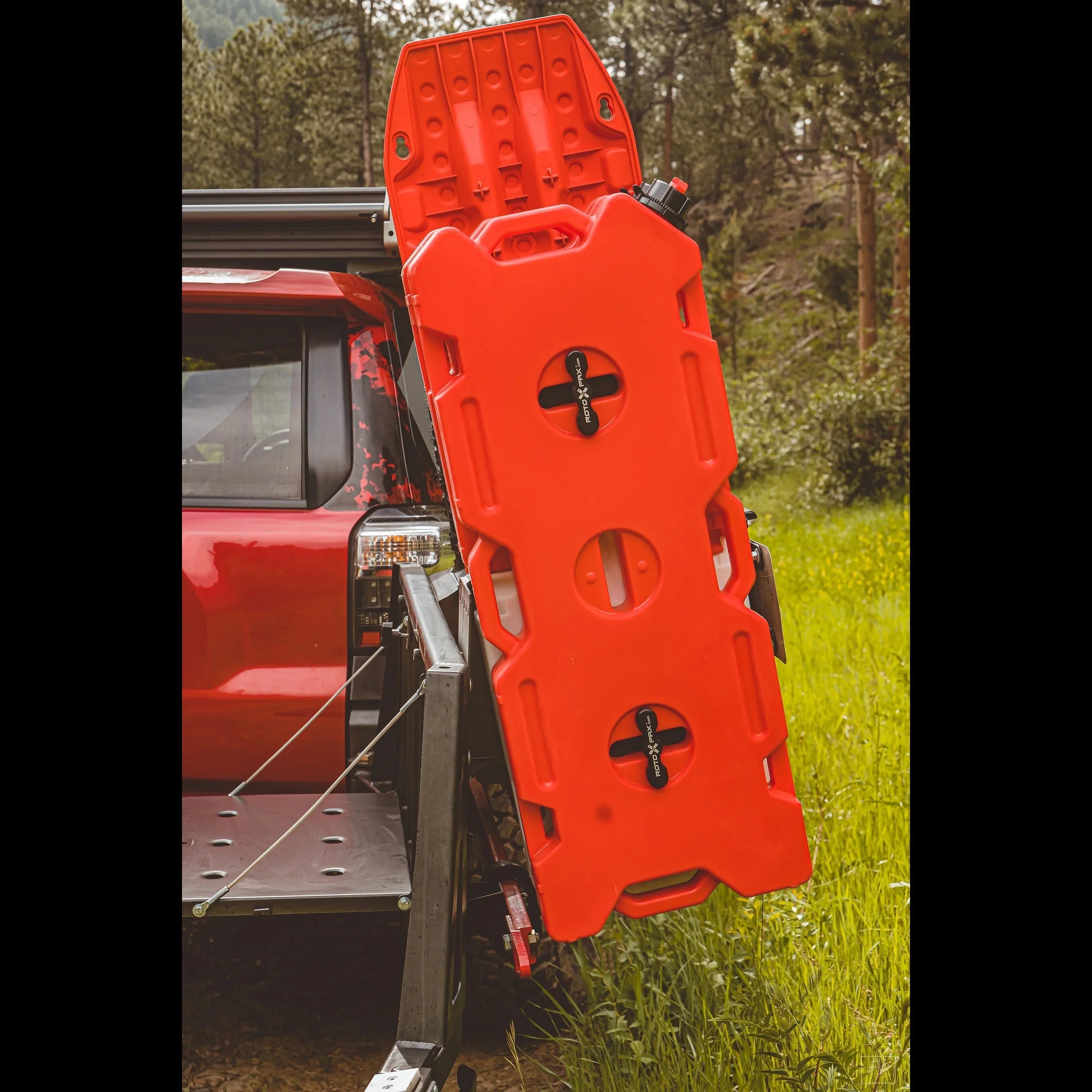 Red overlanding fuel container mounted on a rear swing-out carrier of an off-road vehicle