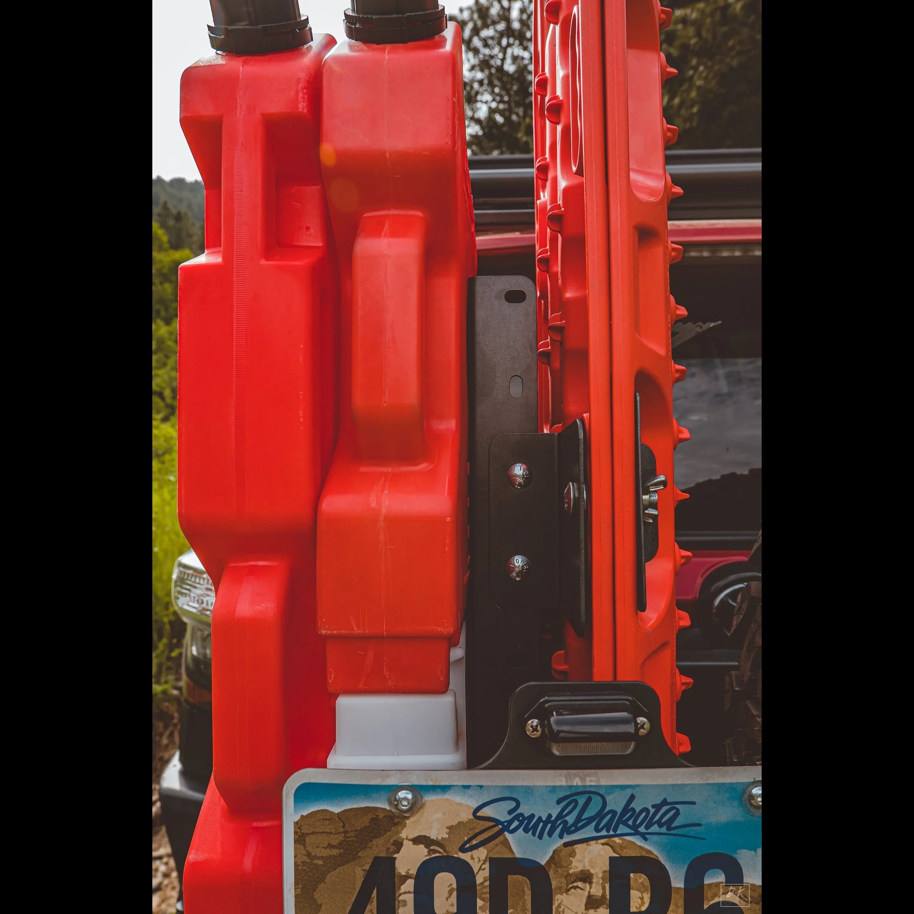 Red fuel canisters and recovery boards mounted on an off-road vehicle tailgate