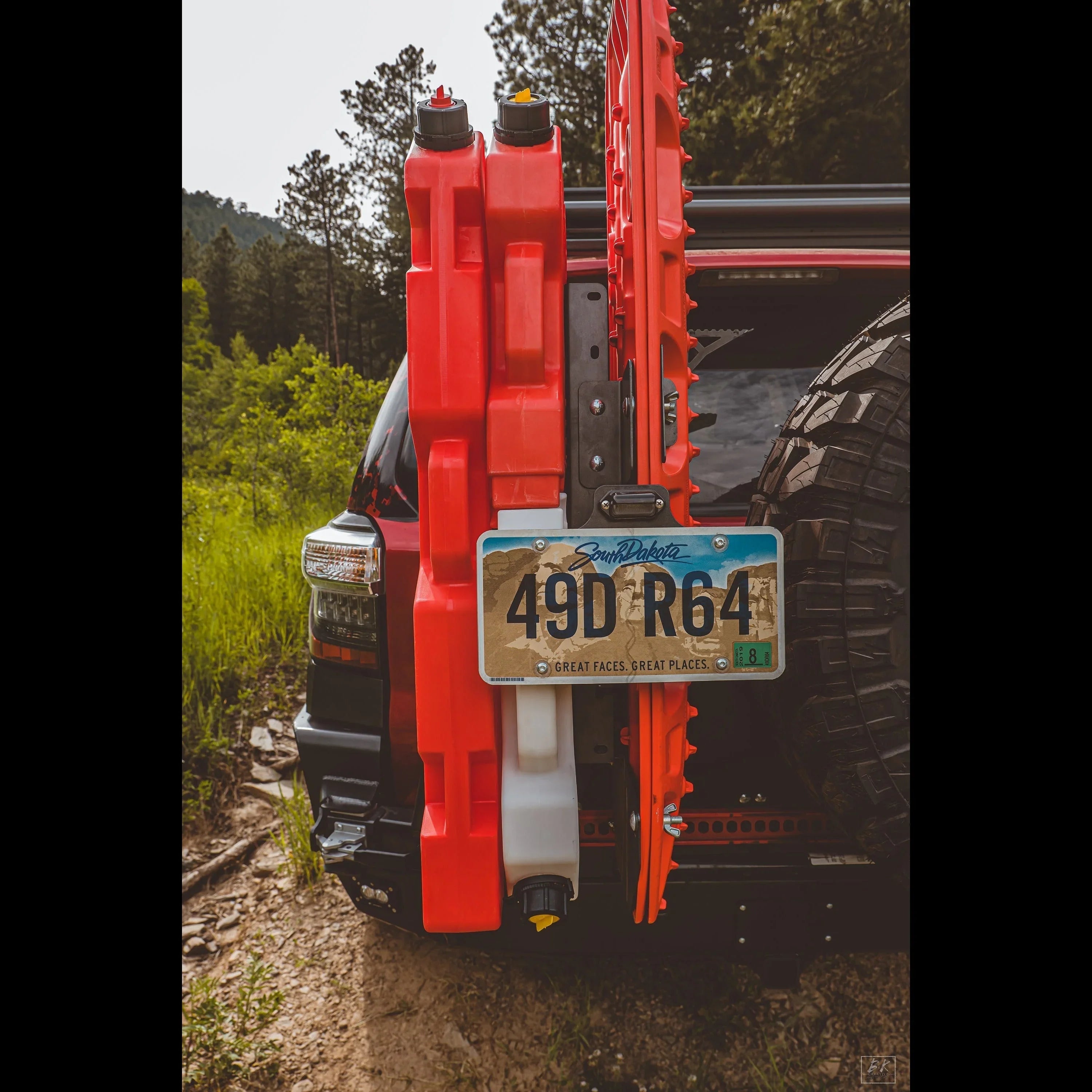 Rear of off-road SUV with recovery gear, fuel canisters, spare tire, and South Dakota plate