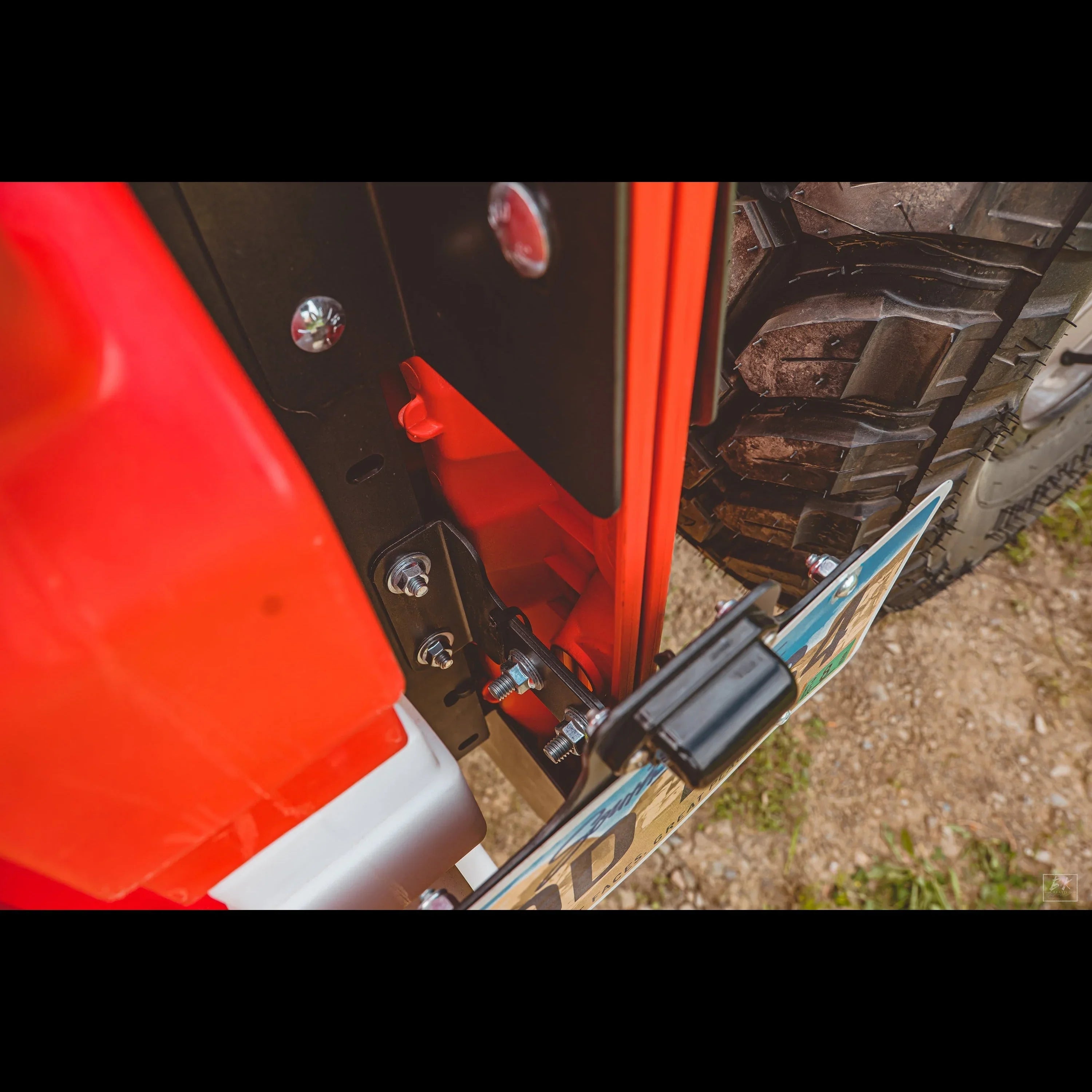 Close-up of Jeep Wrangler tailgate hinge with mounted spare tire and license plate
