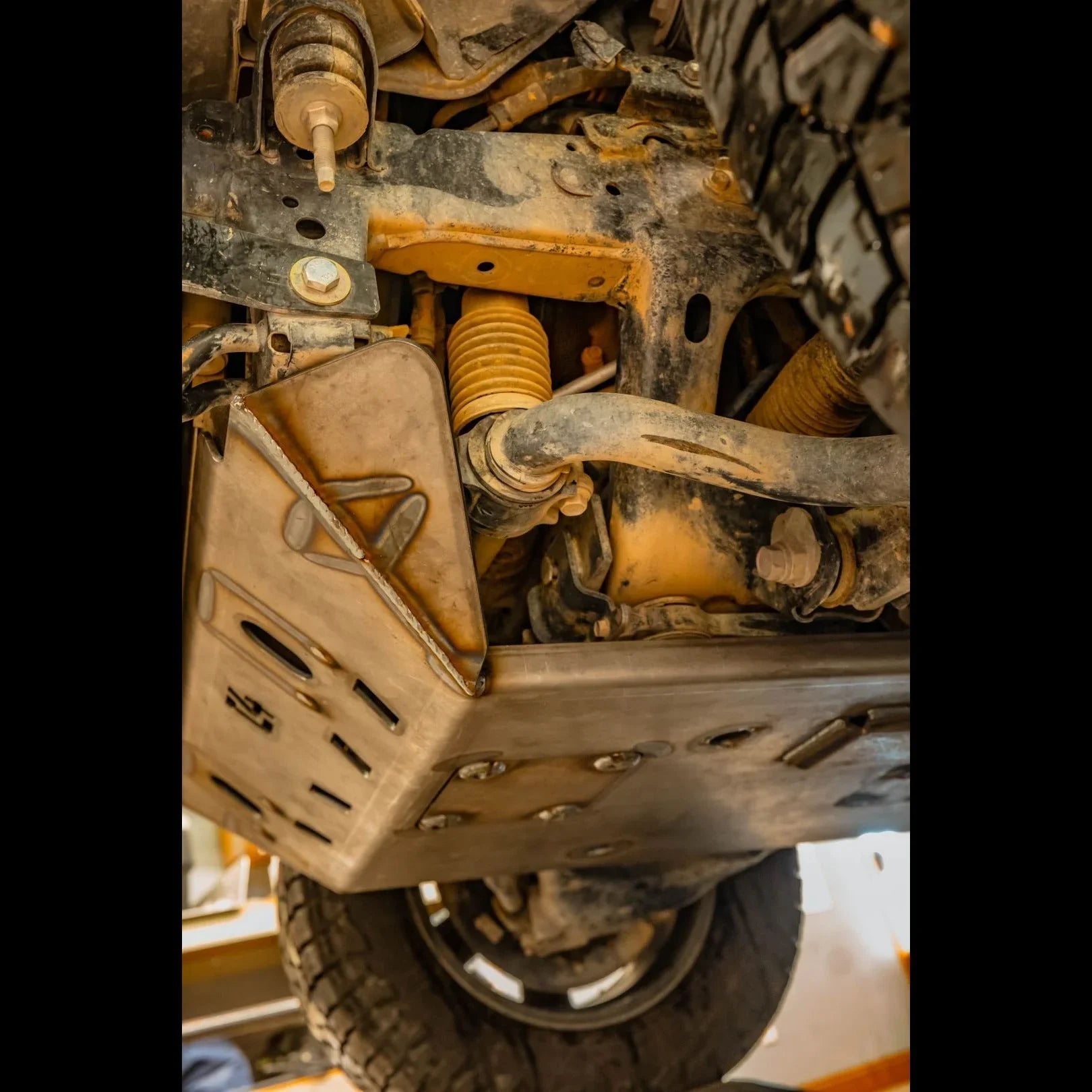 Heavy duty skid plate installed on off-road vehicle undercarriage with suspension detail
