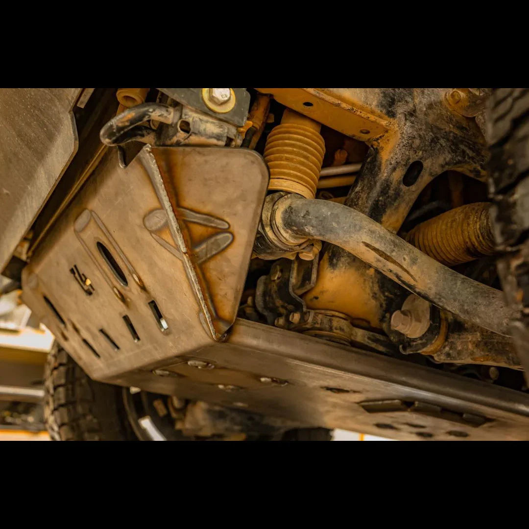 Close-up of an off-road skid plate under a vehicle, protecting suspension and drivetrain parts.