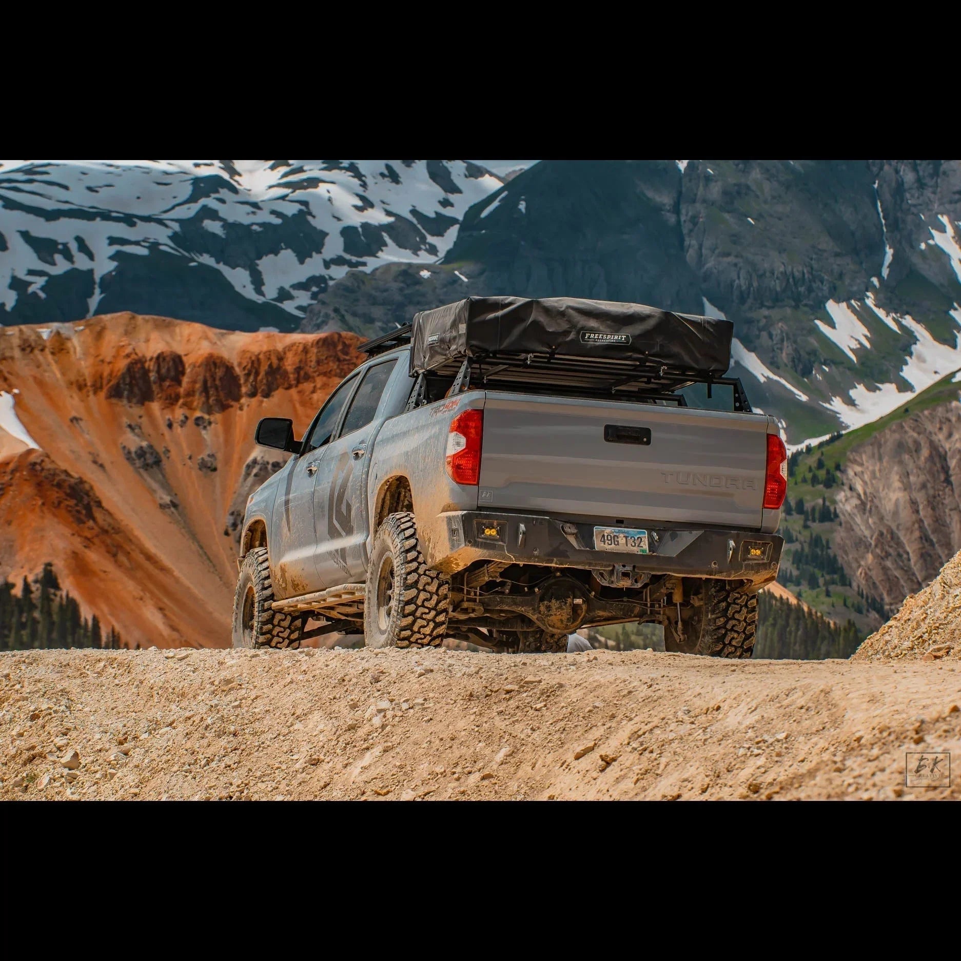 Toyota Tundra off-road truck with rooftop tent in mountain landscape, overlanding gear