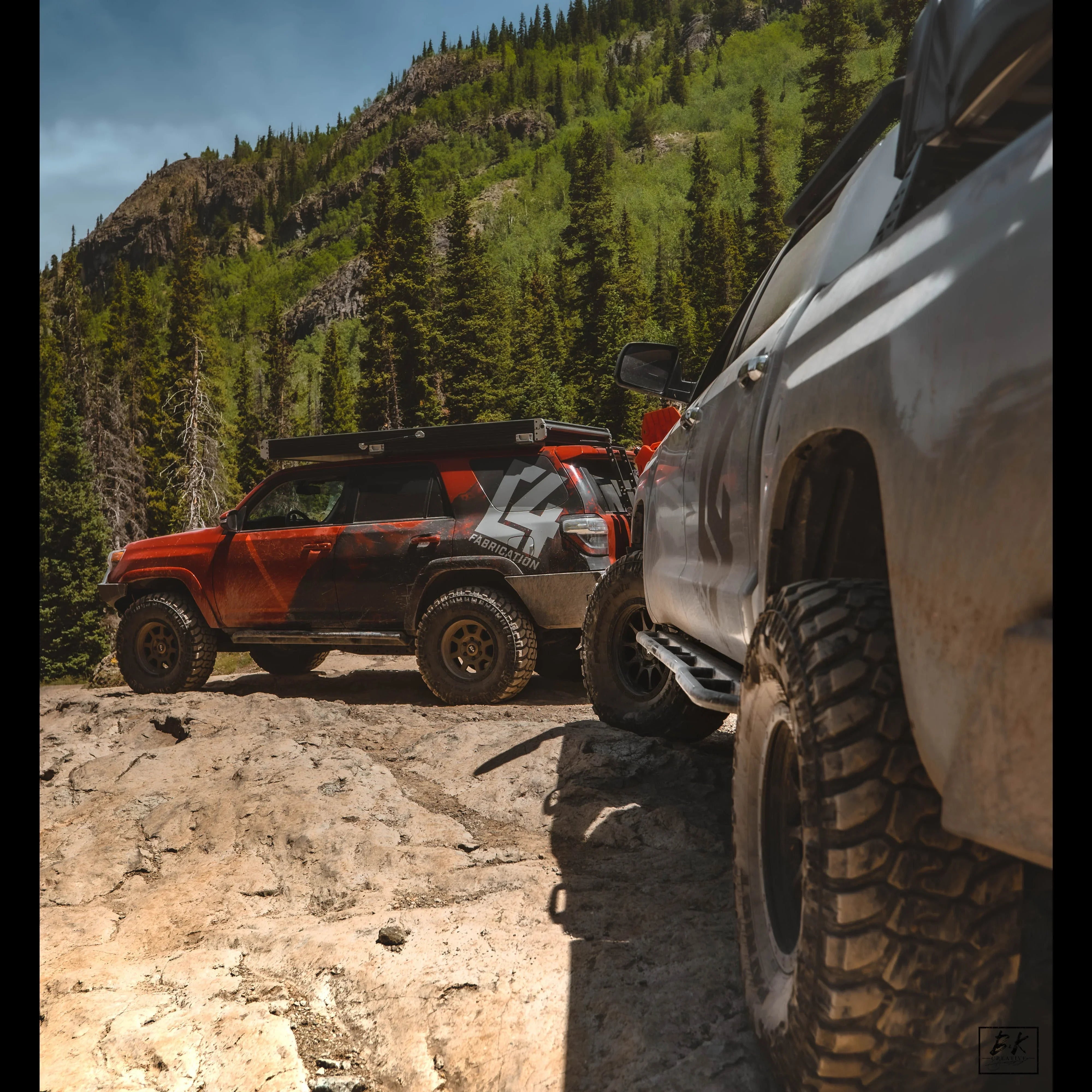 Toyota 4Runner off-road trucks with rock sliders on a rugged mountain trail, forest background
