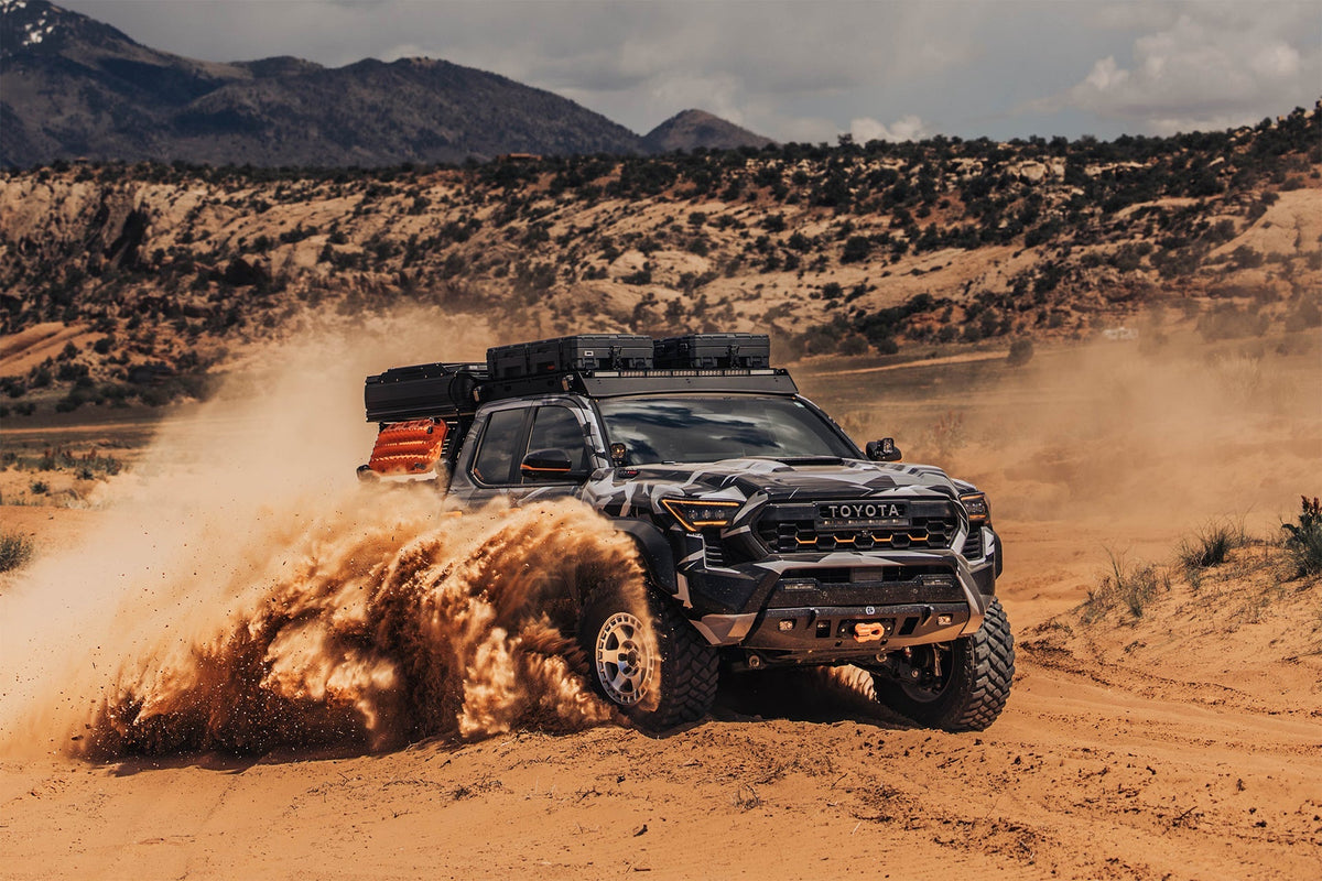 Toyota Tacoma with a steel winch front bumper, light bar and D-ring shackles on a dirt trail
