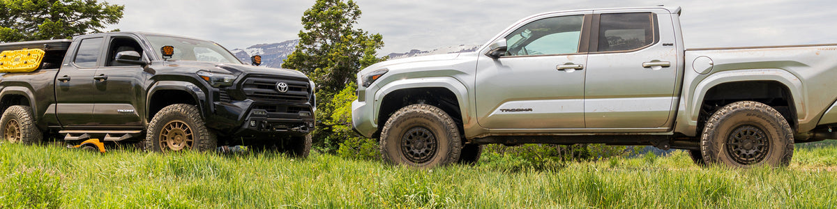 Lifted Toyota Tacoma with aftermarket coilovers and larger all-terrain tires on a dirt trail
