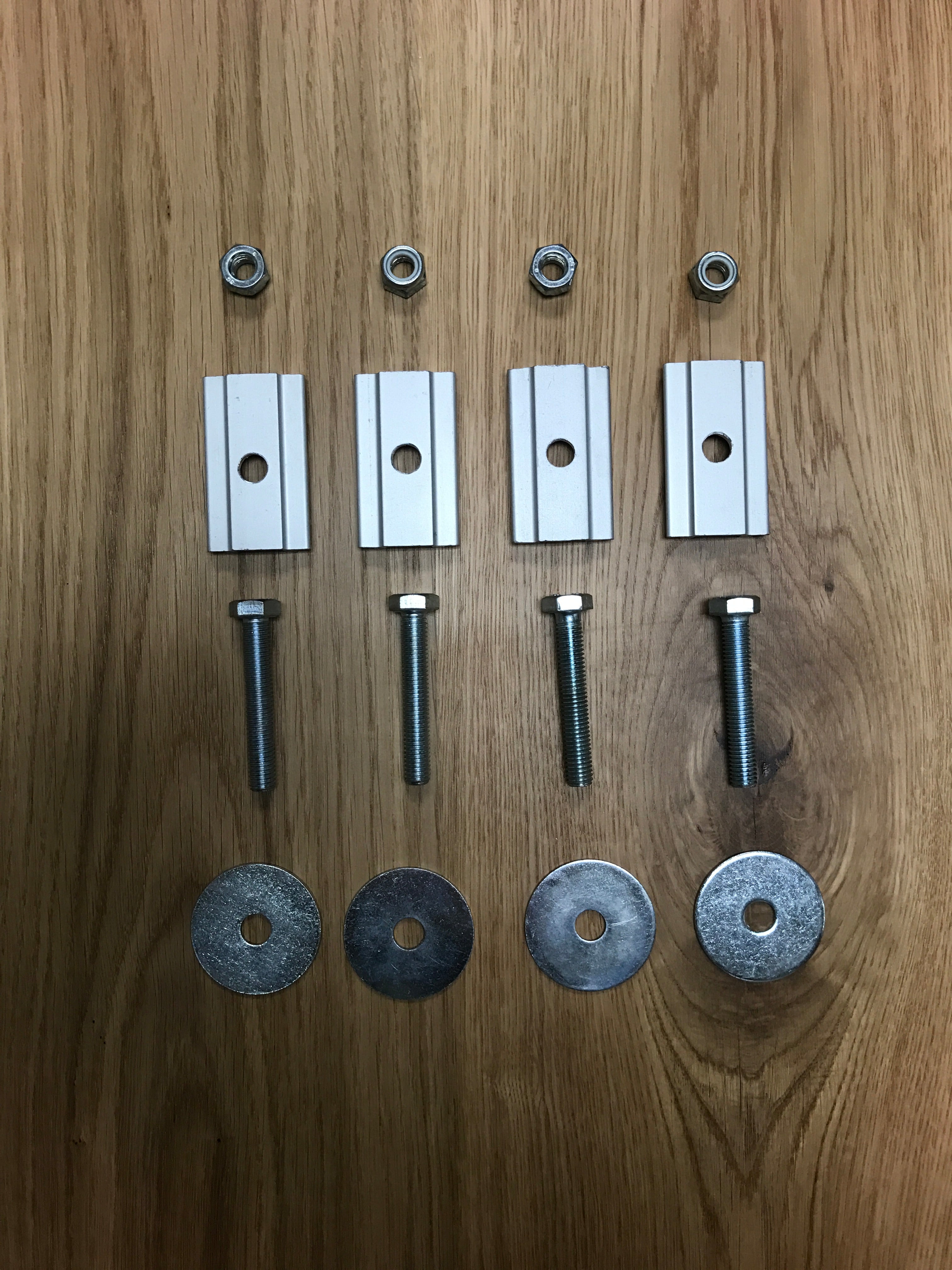 Overland vehicle mounting hardware kit with T-slot nuts, bolts, and washers on wood surface