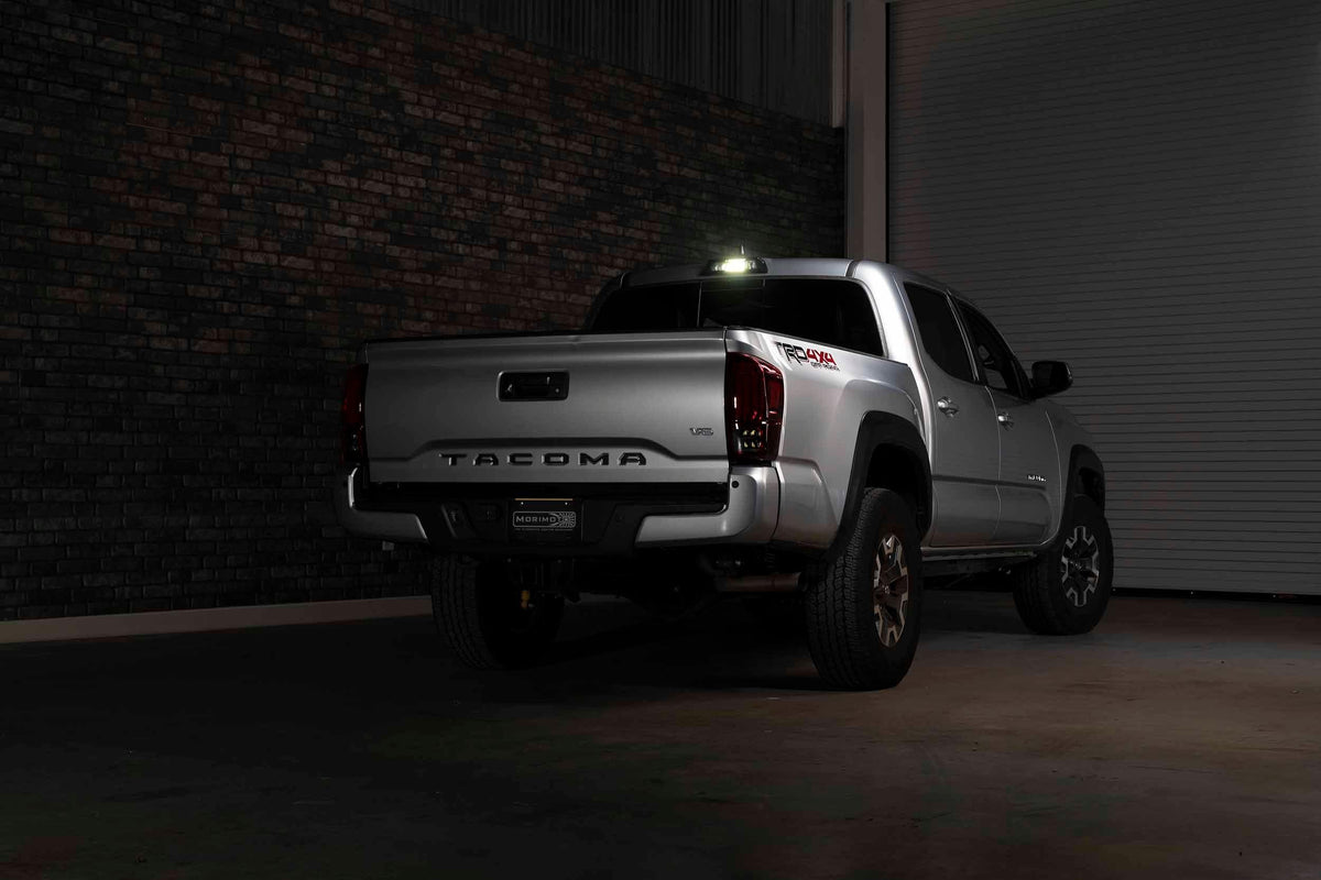 Silver Toyota Tacoma TRD Off Road pickup truck with aftermarket lighting, parked indoors