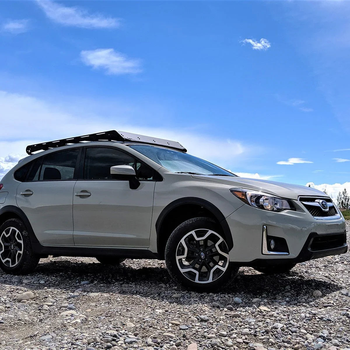 Subaru Crosstrek with roof rack parked on rocky terrain under blue sky, adventure ready