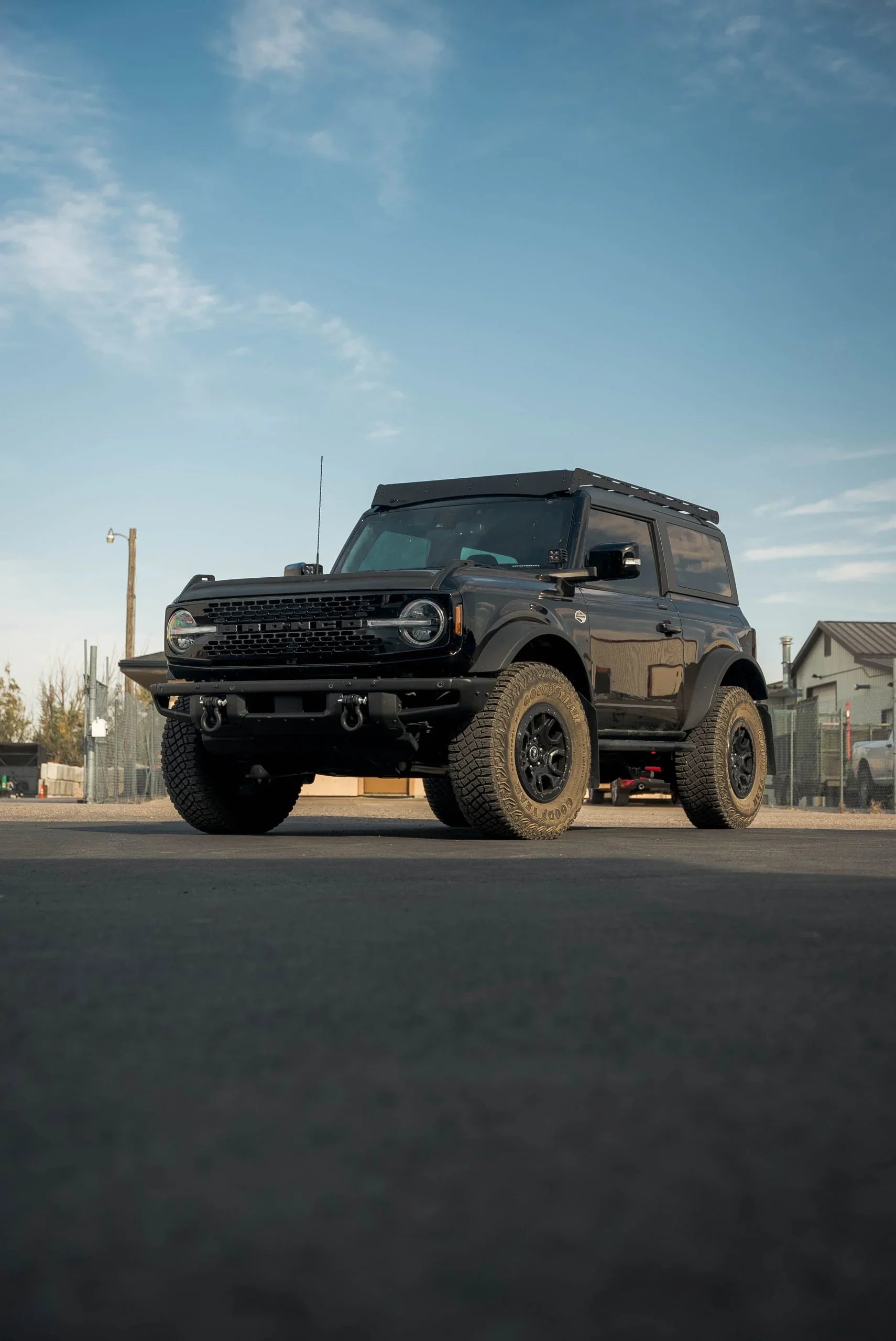 Black 2-door Ford Bronco with off-road tires and roof rack in an outdoor lot