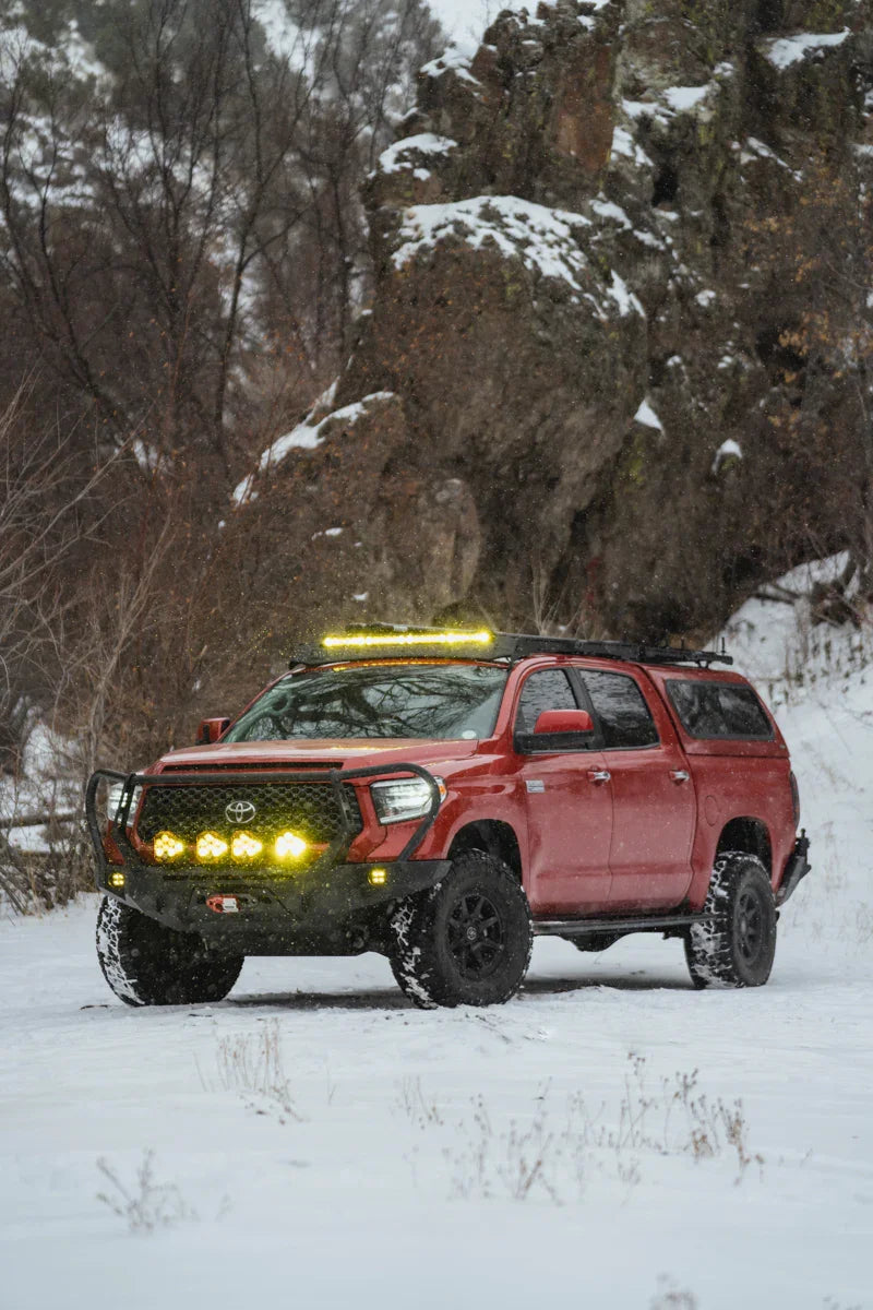 Toyota Tundra with off-road adventure bumper and yellow lights in snowy landscape