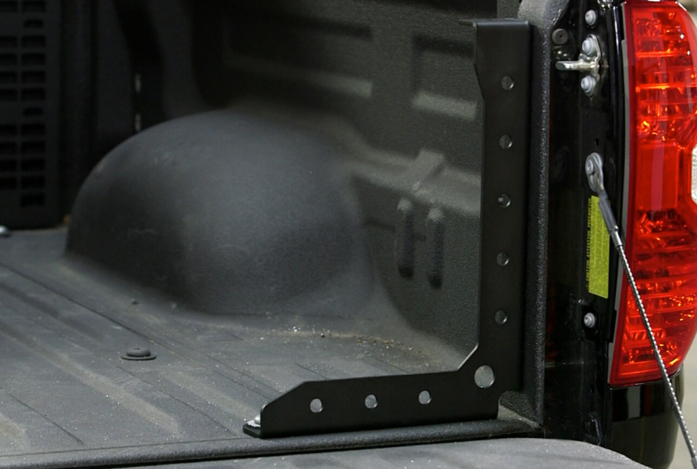 Black metal bed rack bracket installed in a truck bed for overland gear mounting