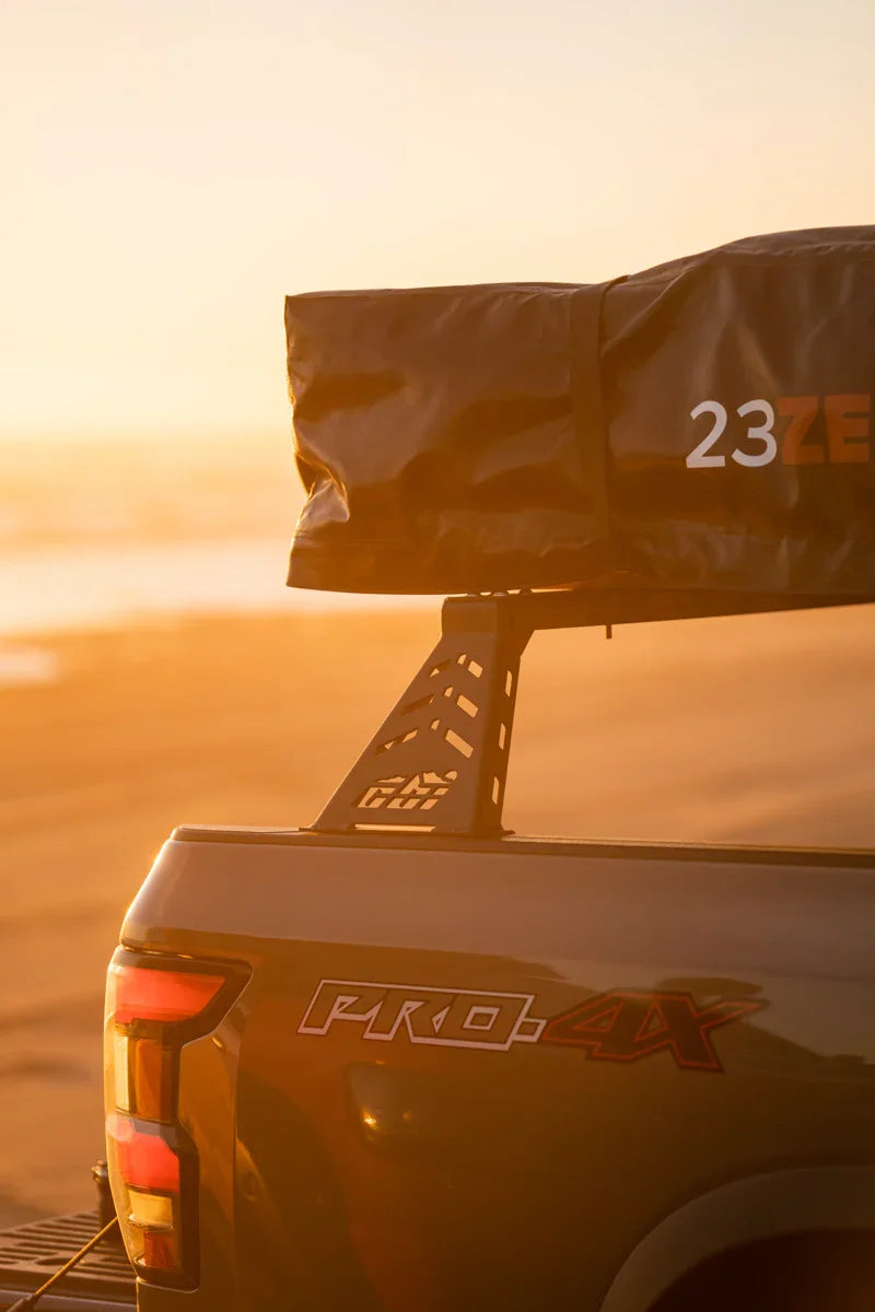 Nissan PRO-4X pickup with overland bed rack and rooftop tent at sunset on the beach