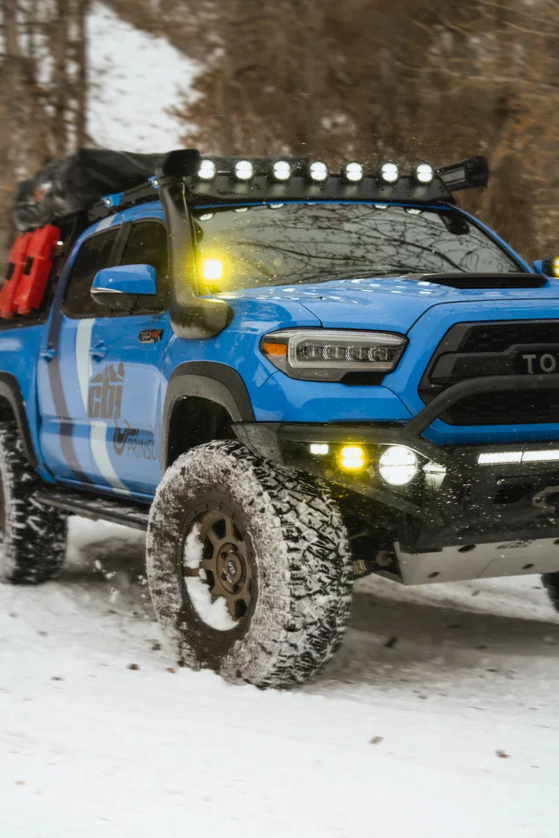 Toyota Tacoma with off-road gear and LP4 wind deflector driving in snowy forest