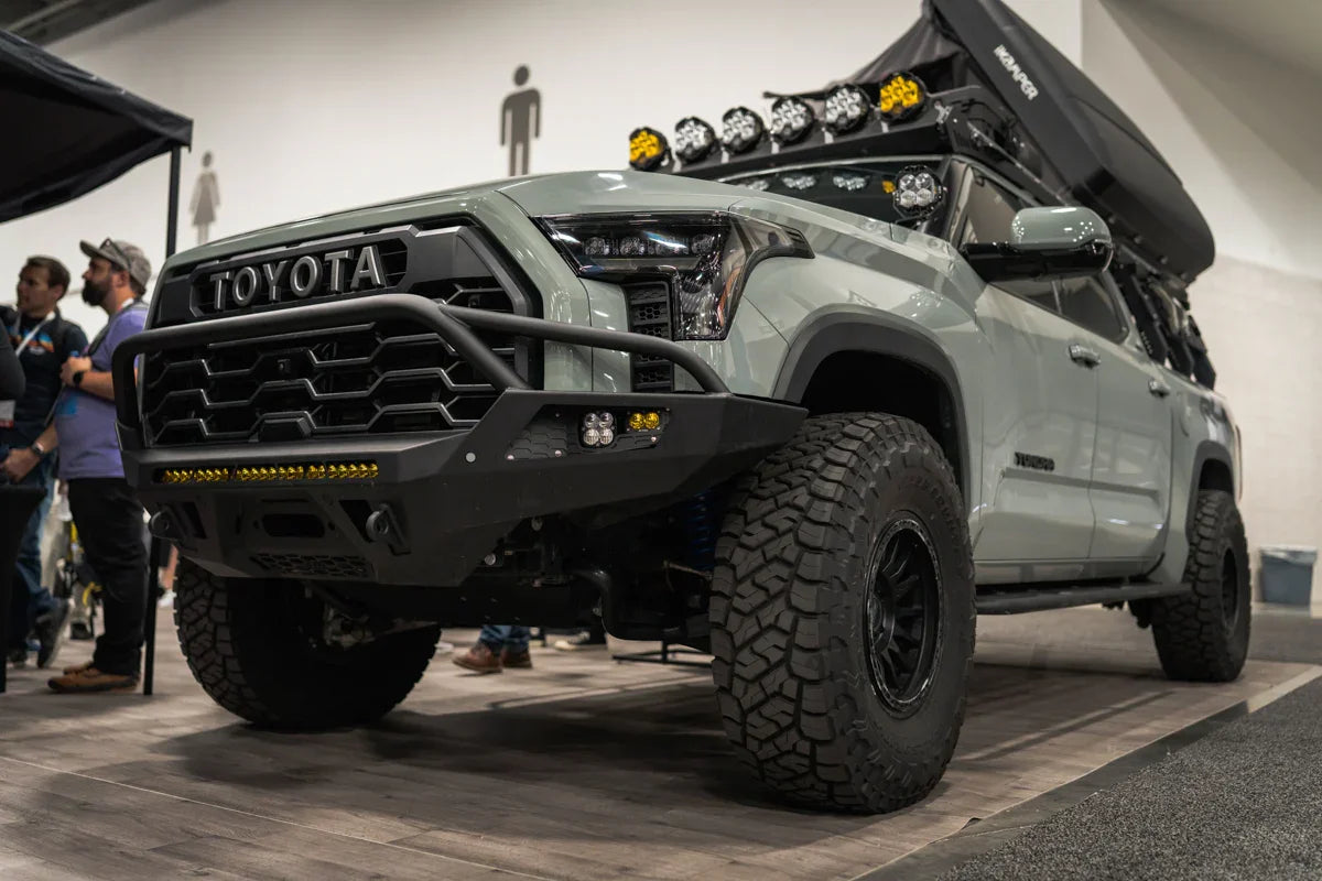 Toyota Tundra with off-road Baja bumper, roof rack lights, and rugged tires at expo