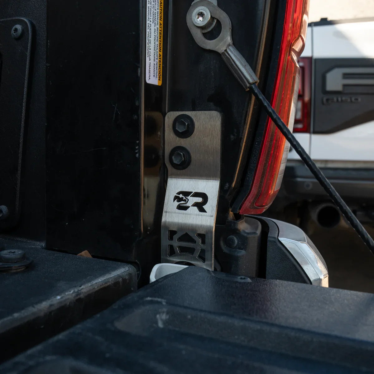 Toyota Tacoma tailgate theft protector metal bracket installed near taillight