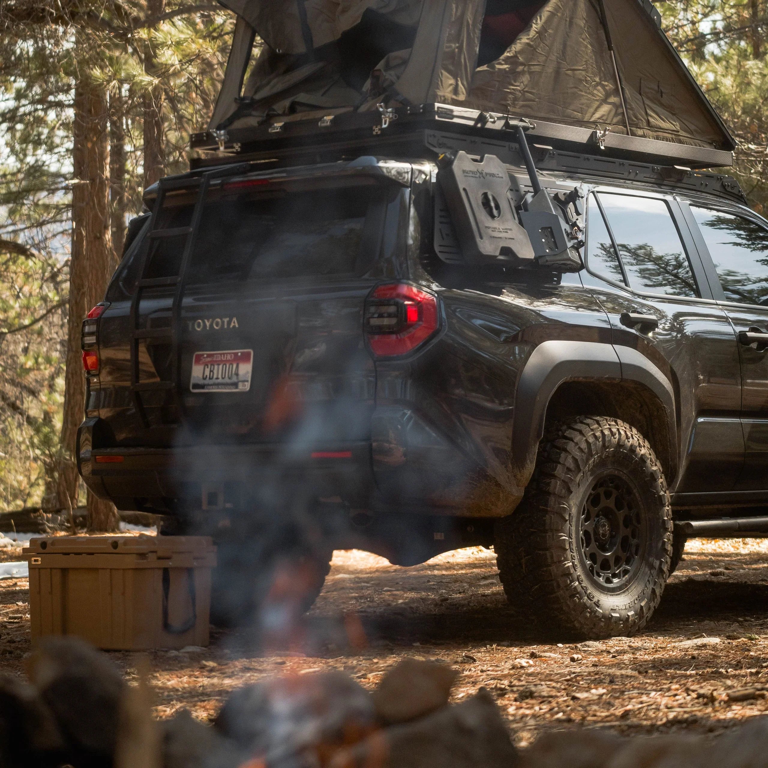 Toyota 4Runner with rooftop tent, ladder, and camping gear in forest setting