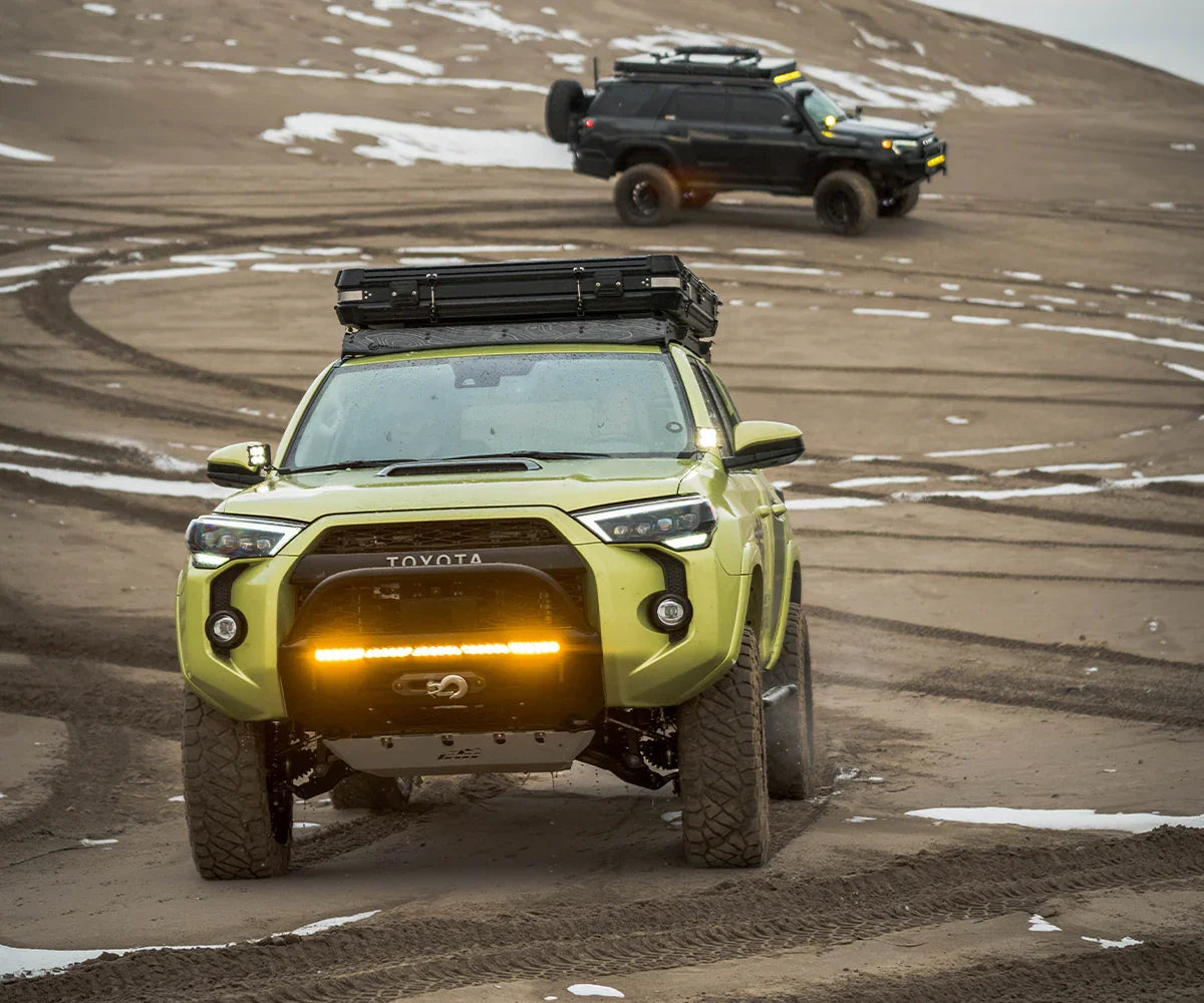 Toyota 4Runner SUV with off-road accessories driving on sand dunes with snow patches