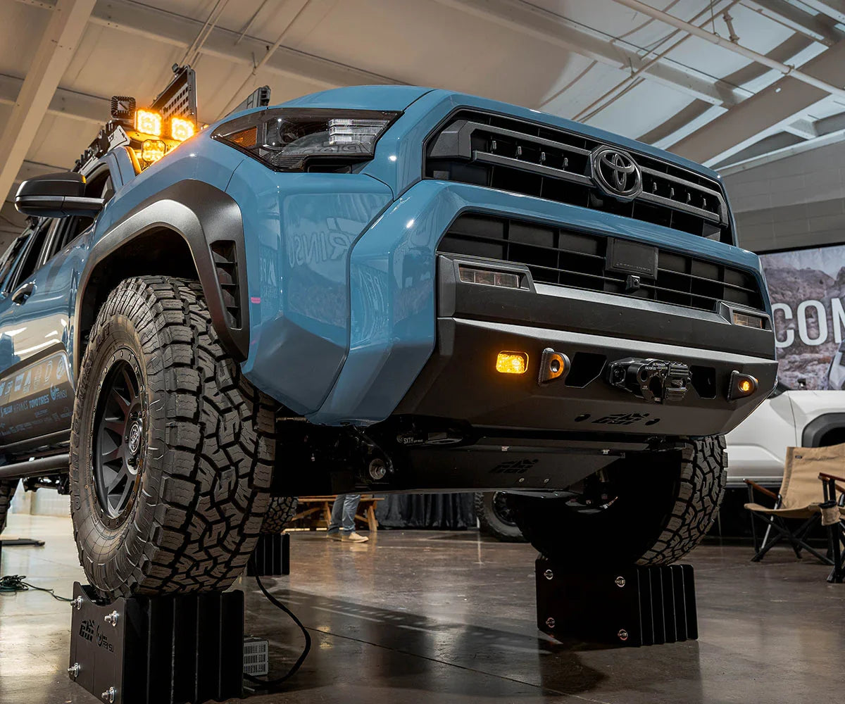 Blue Toyota 4Runner with off-road tires, aftermarket bumper, and auxiliary lights on display