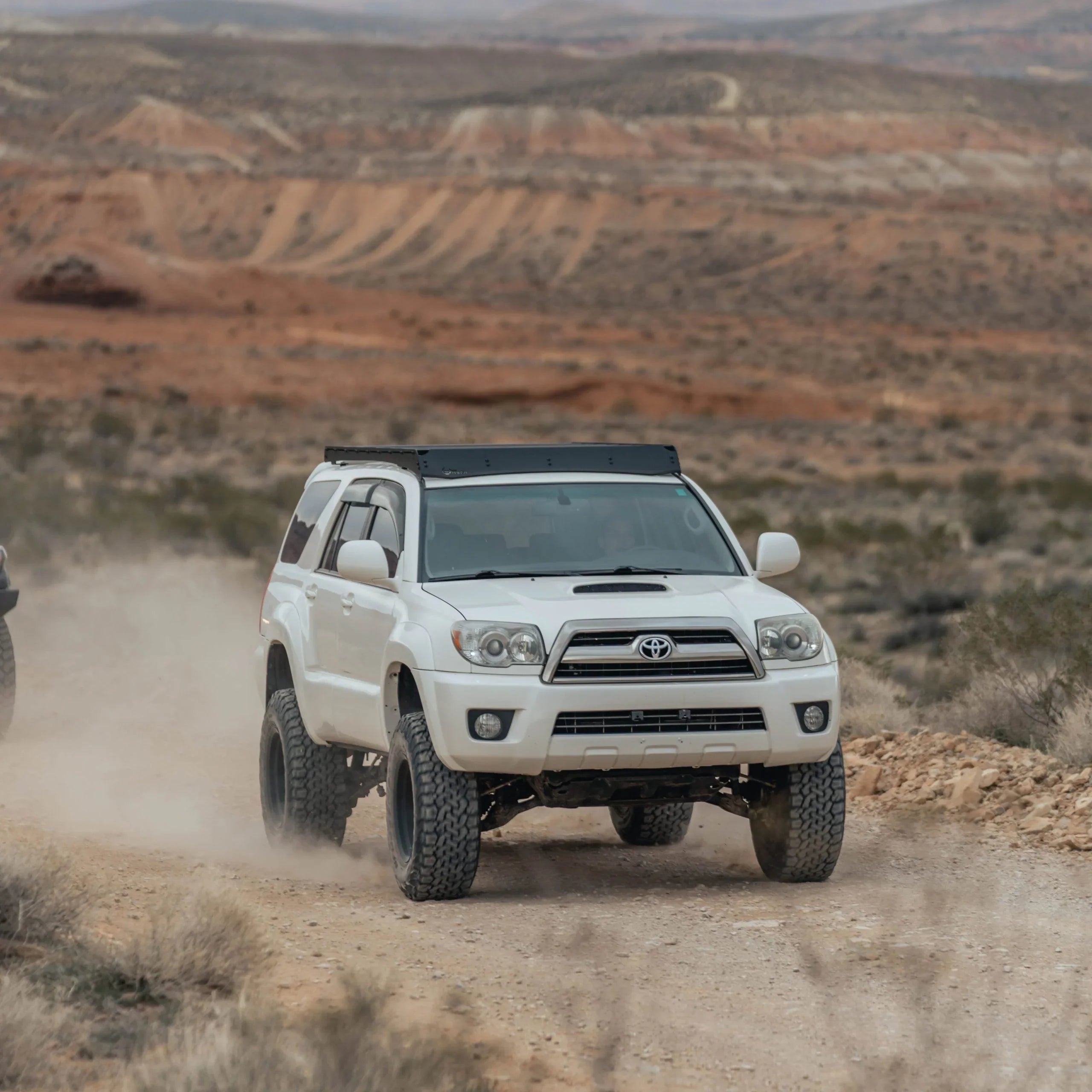 Toyota 4Runner with roof rack driving off-road in a desert landscape