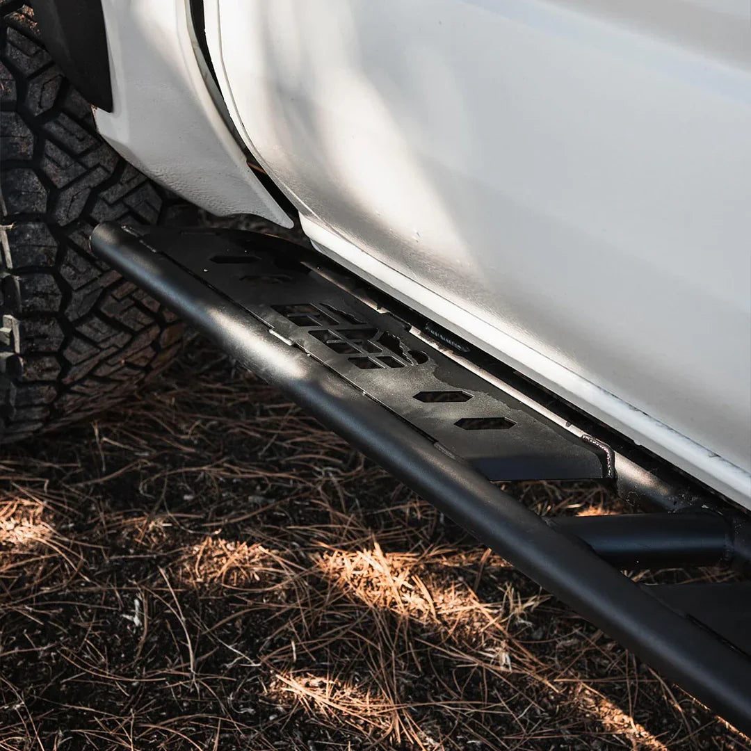 Toyota Tacoma rock sliders black steel off-road accessory side step on white truck