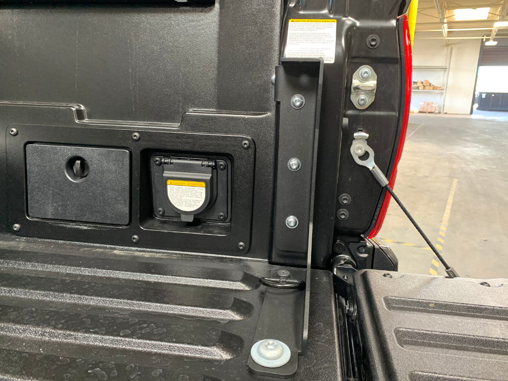 Truck tailgate accessory bracket mounted near power outlet, suited for overlanding gear setup