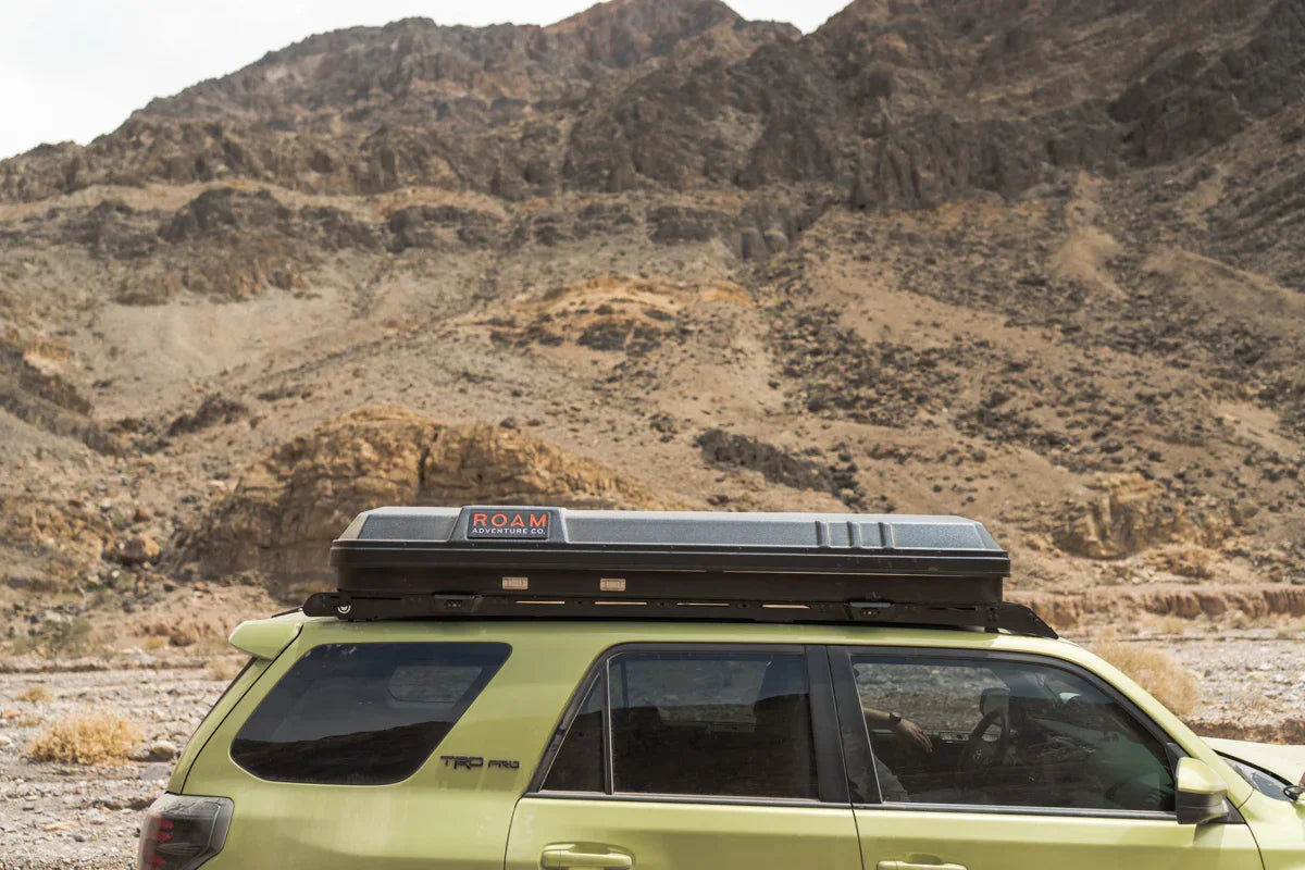 Toyota 4Runner with roof rack cargo box in a rocky desert landscape